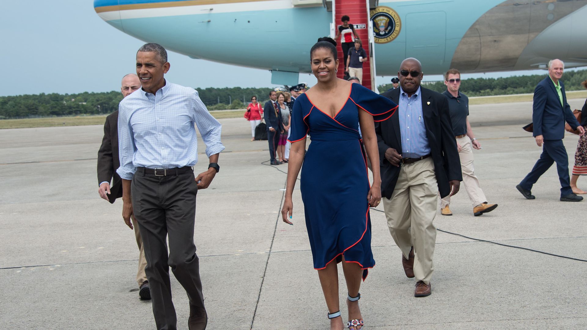 US President Barack Obama and First Lady Michelle Obama walk to greet wellwishers at Cape Cod Air Force Station in Massachusetts on August 6, 2016 a