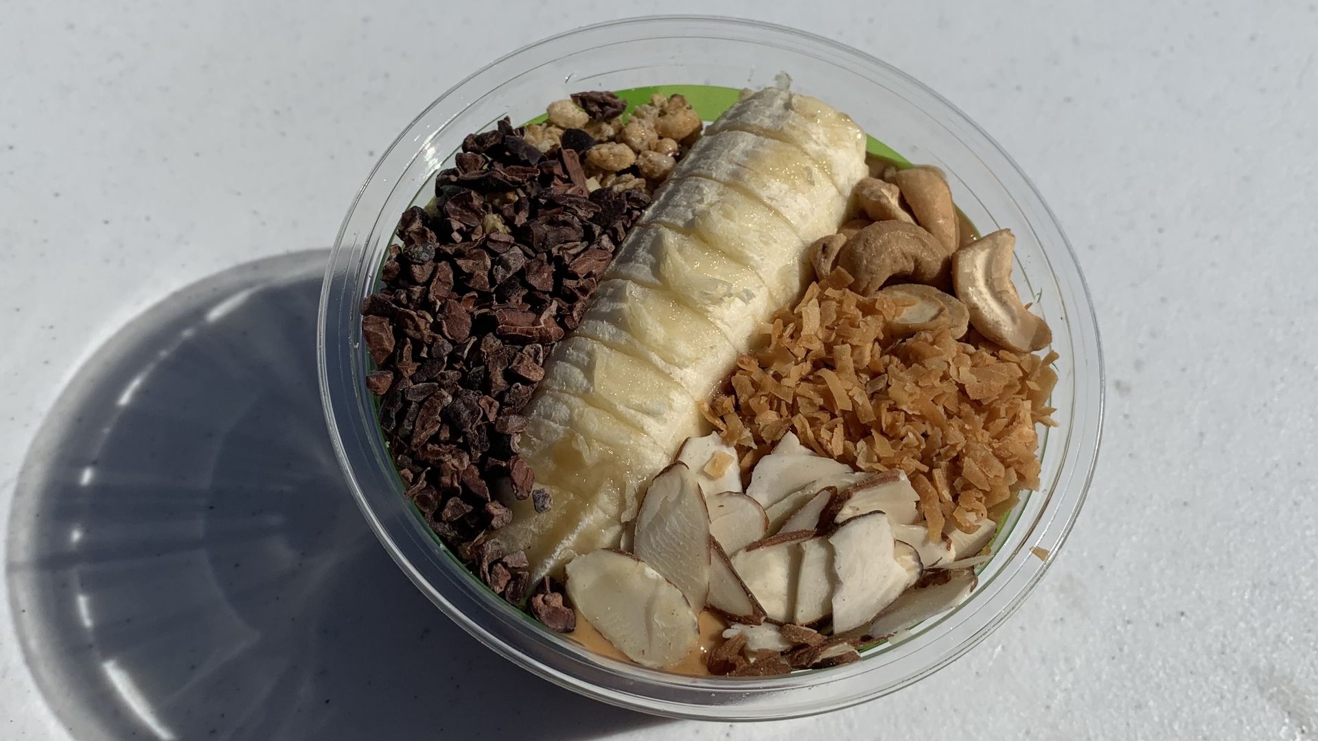 the amazon protein bowl with açaí and peanut butter topped with granola, banana, almonds, cashews, cacao nibs and coconut shavings