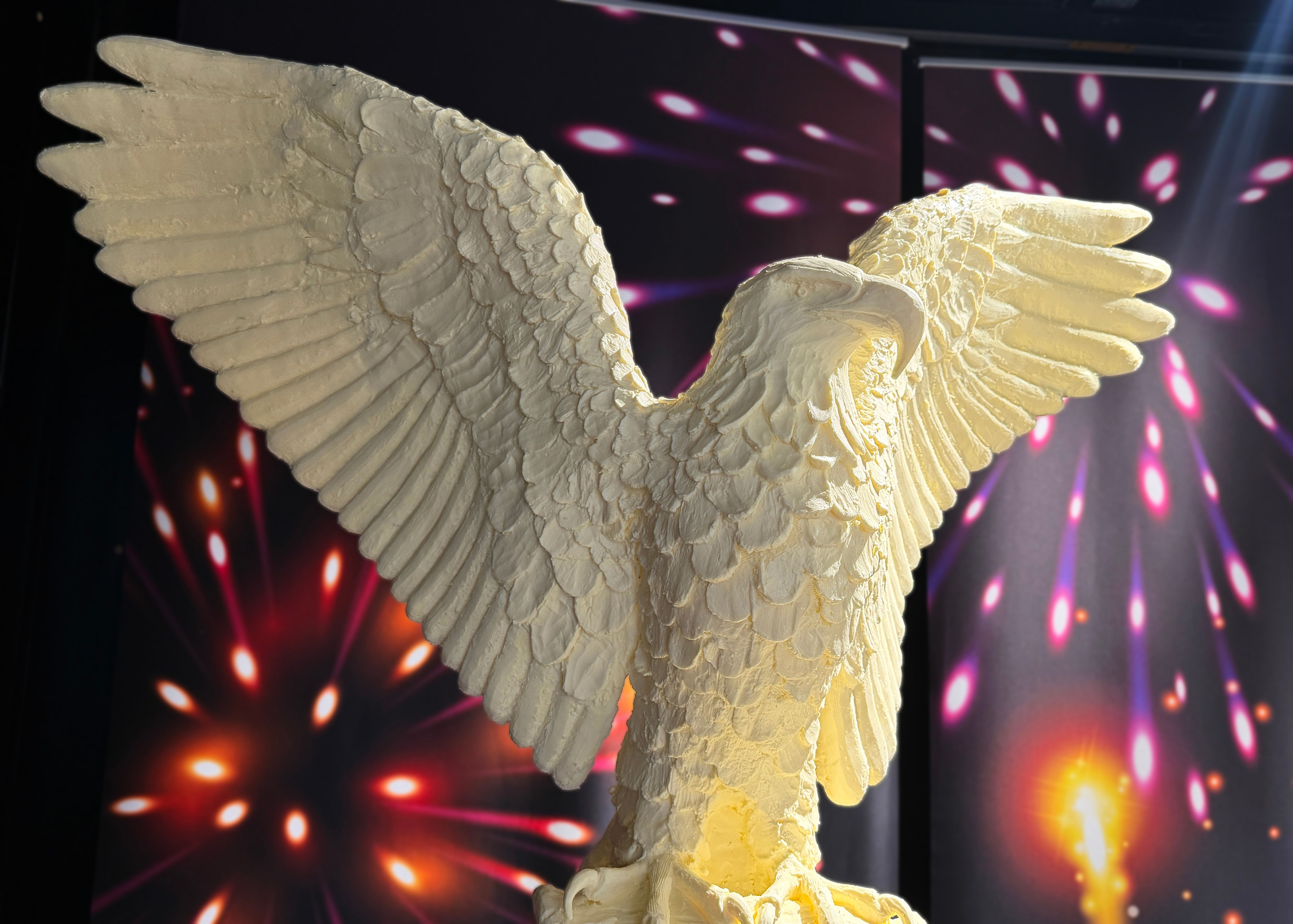 A bald eagle sculpted out of butter with its wings spread, amid a backdrop of fireworks.