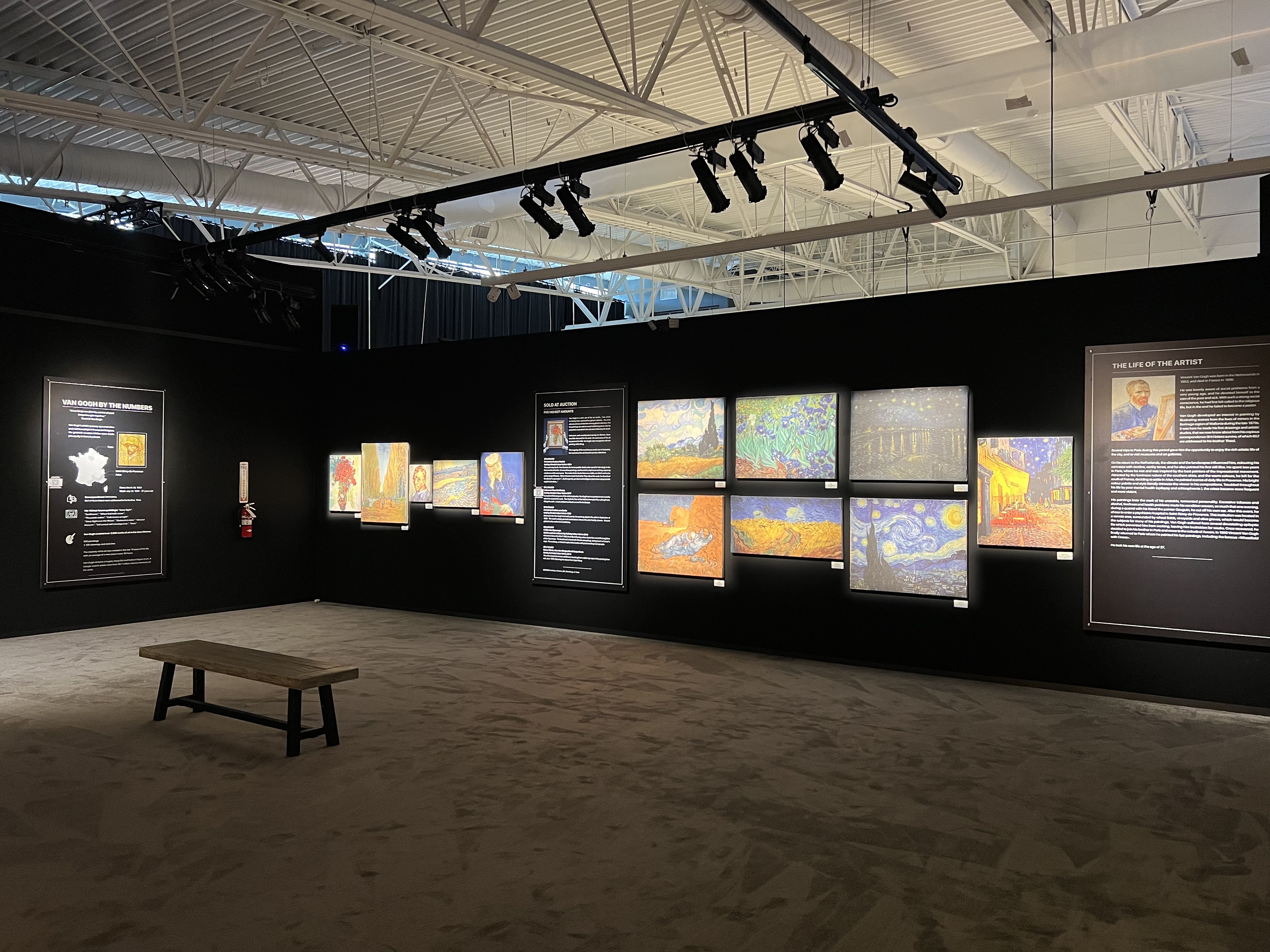 A room witih paintings, a bench and descriptors of those paintings