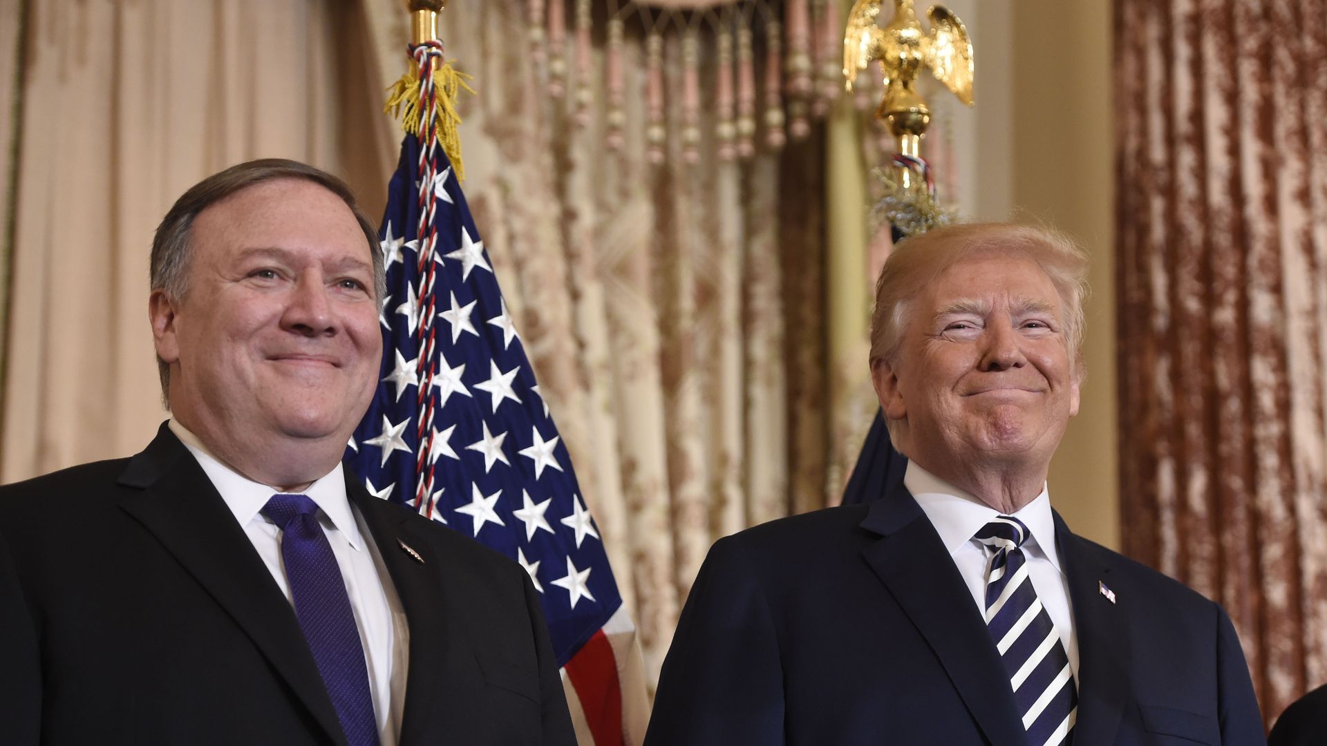 Mike Pompeo and Trump stand before an American flag.