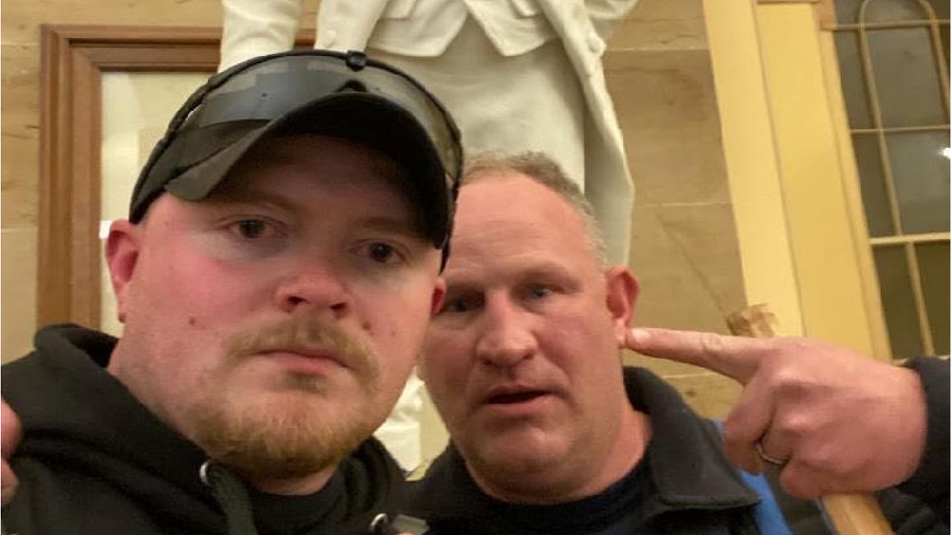 A photo included as an exhibit in the criminal complaint released by authorities shows the men posing in front of the statue with their fingers raised. 
