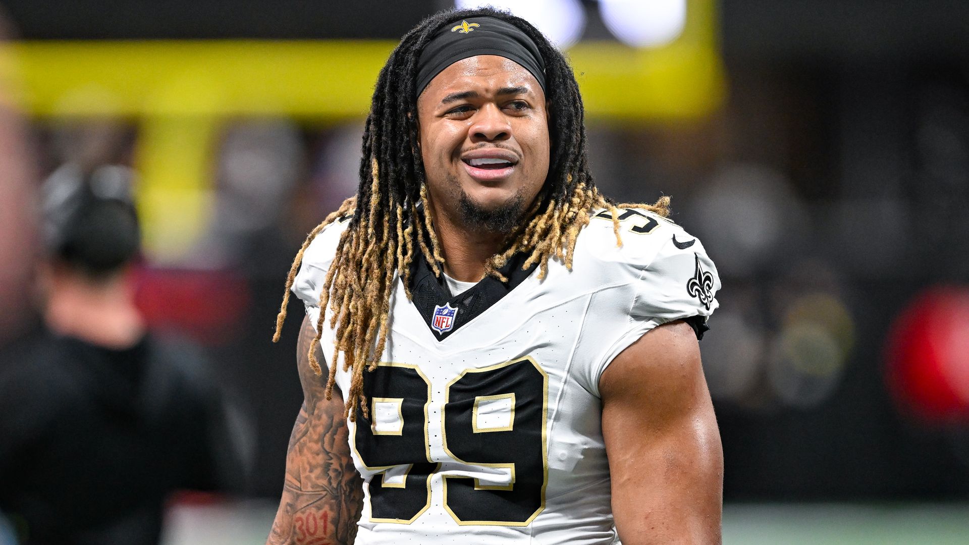 A man wearing a No. 99 Saints football jersey looks confused as he reacts to something off-camera.