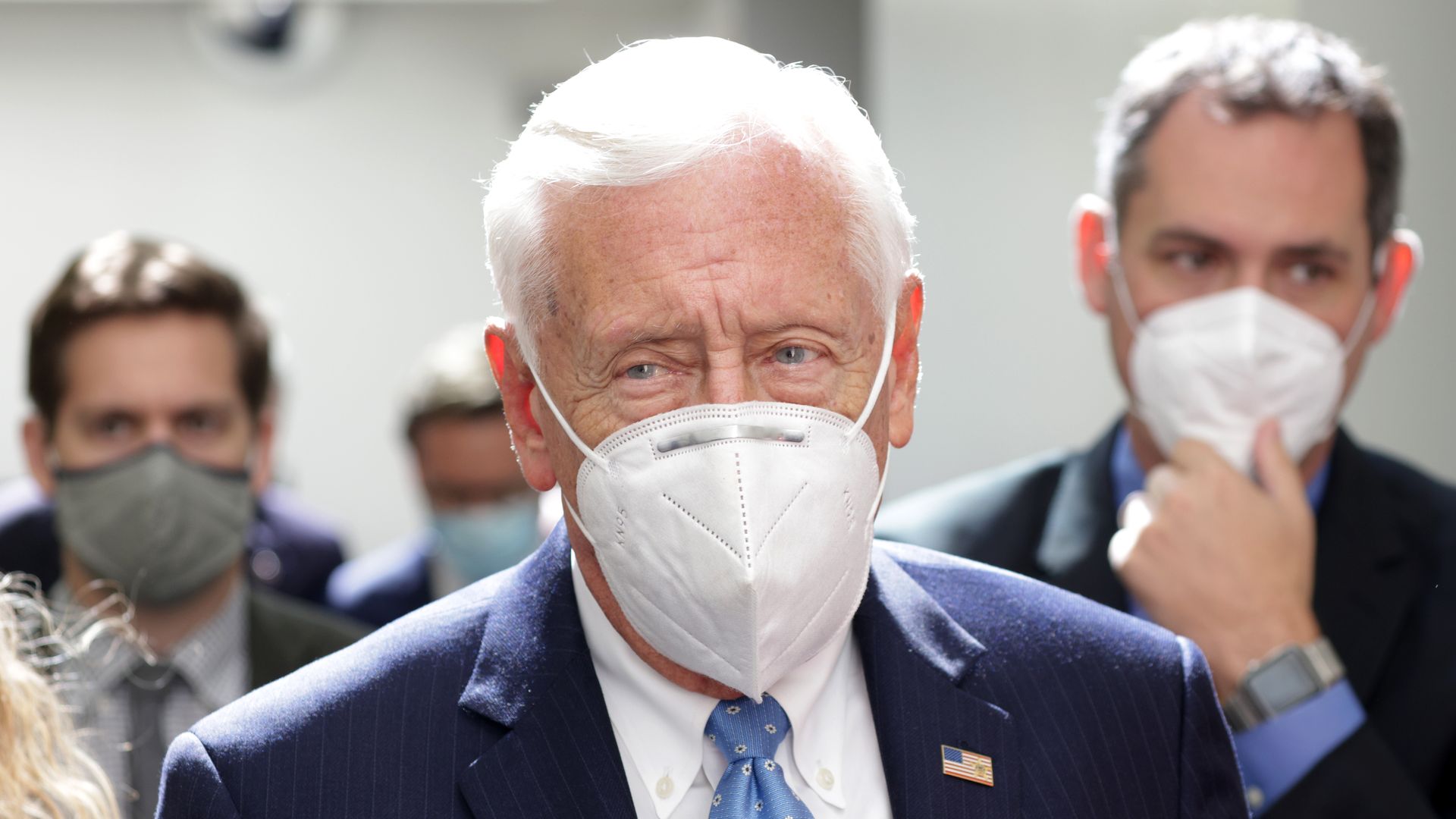 Photo of Steny Hoyer wearing a mask as he is surrounded by staffers