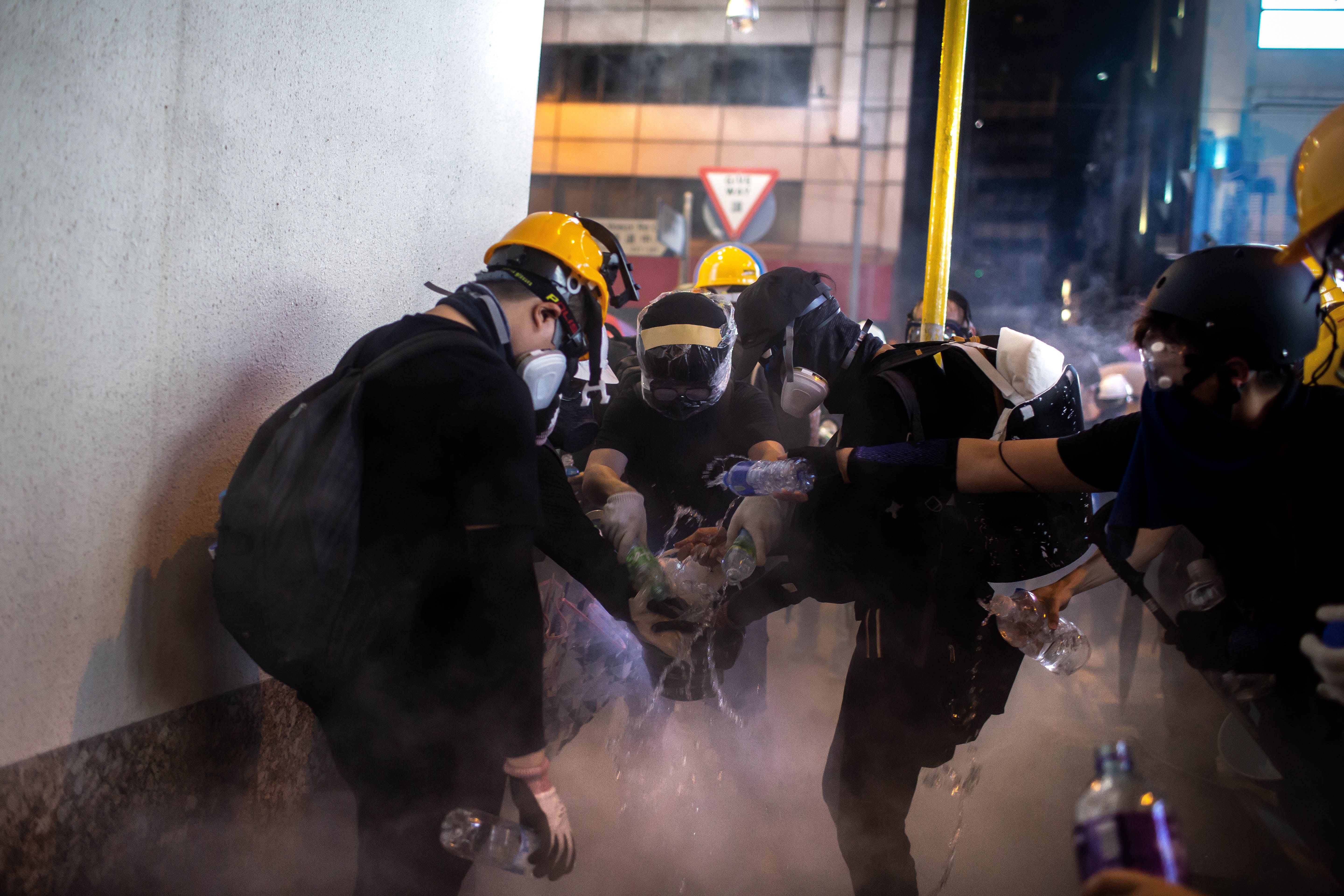 Protesters extinguish a tear gas canister by covering it and pouring on water during a demonstration.