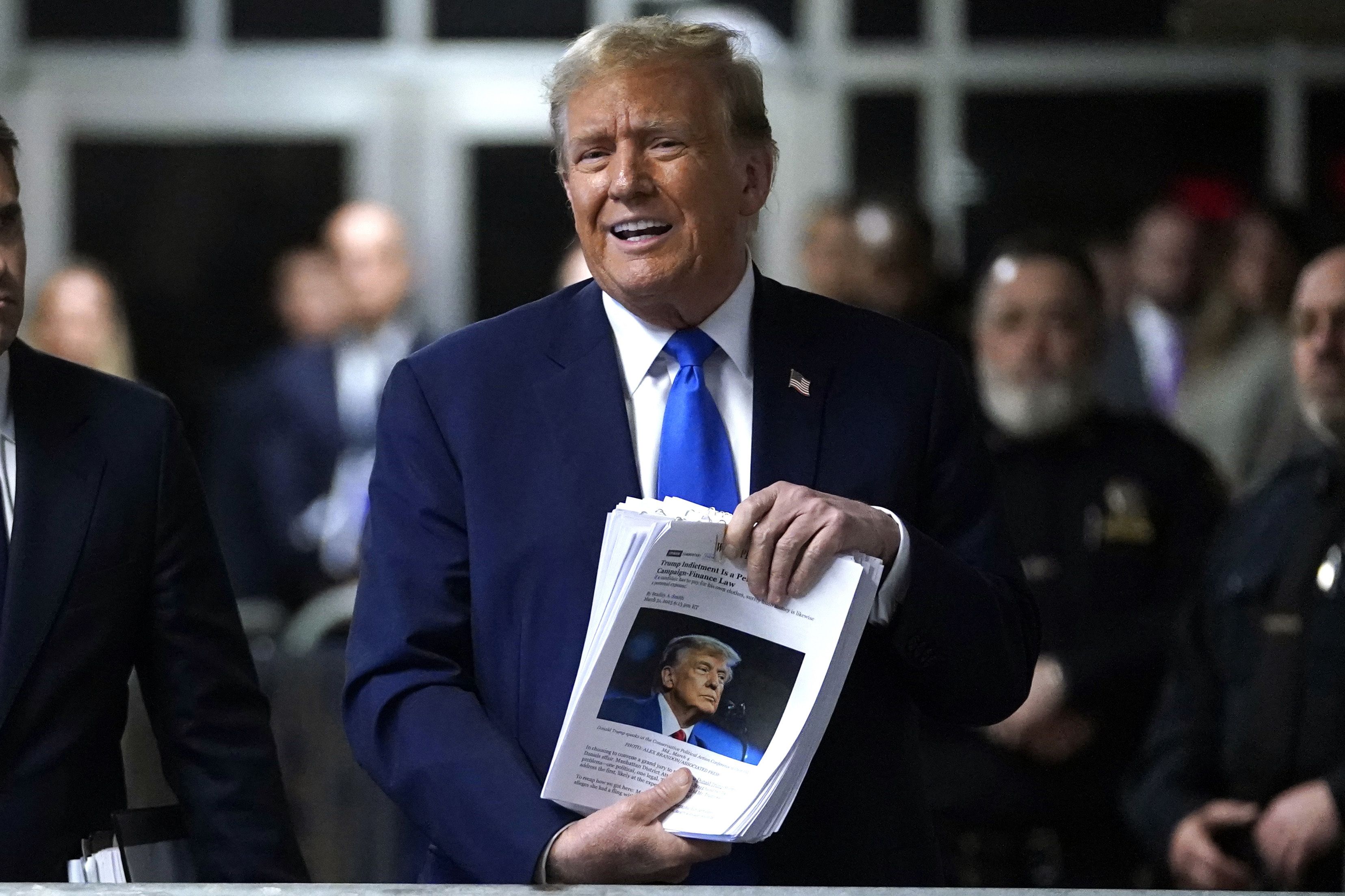 Former President Trump holds up printouts of news stories following yesterday's session in Manhattan criminal court.