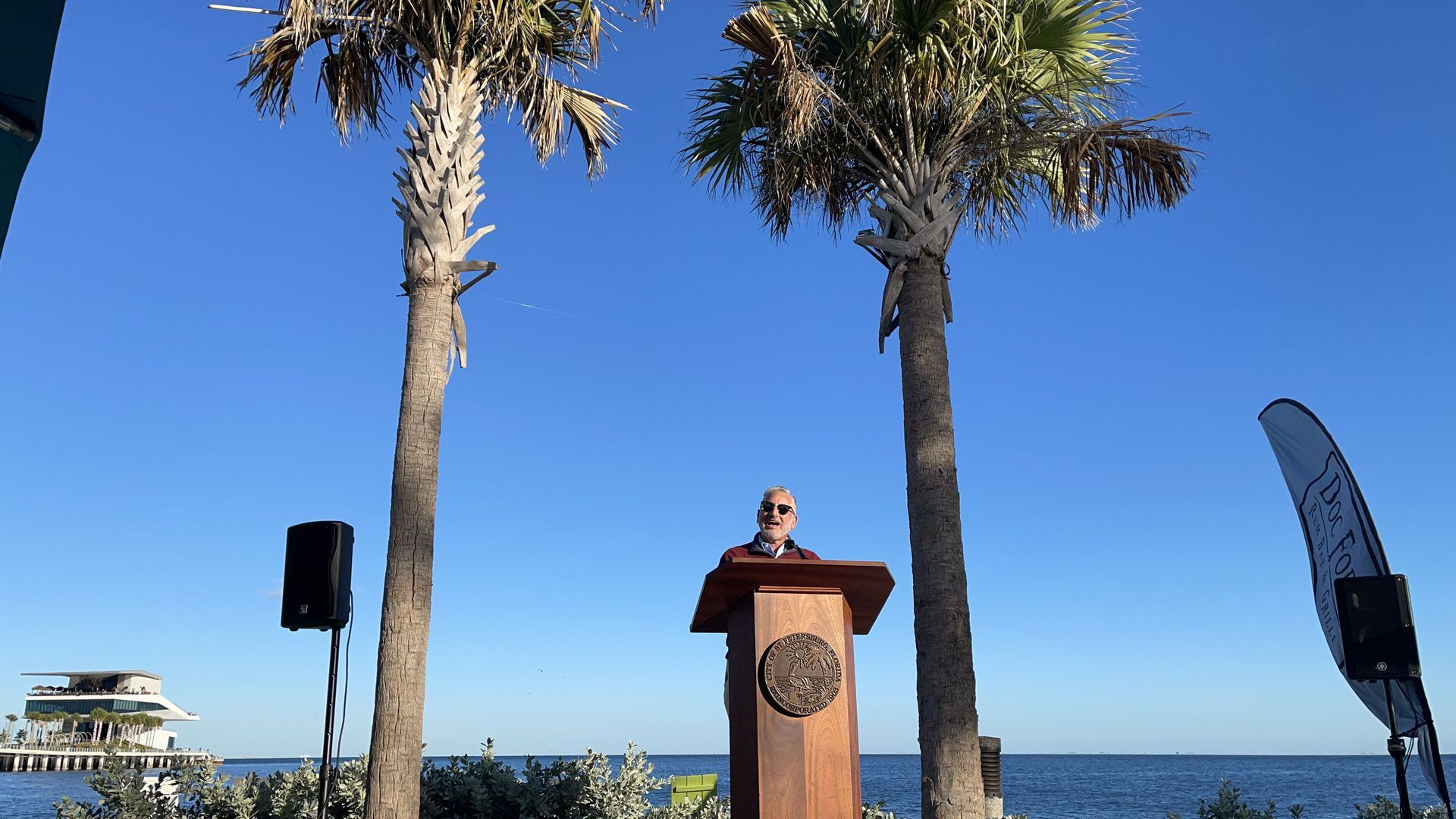 St. Petersburg Mayor Rick Kriseman gives his farewell speech at Doc Ford's with palm trees in the background,