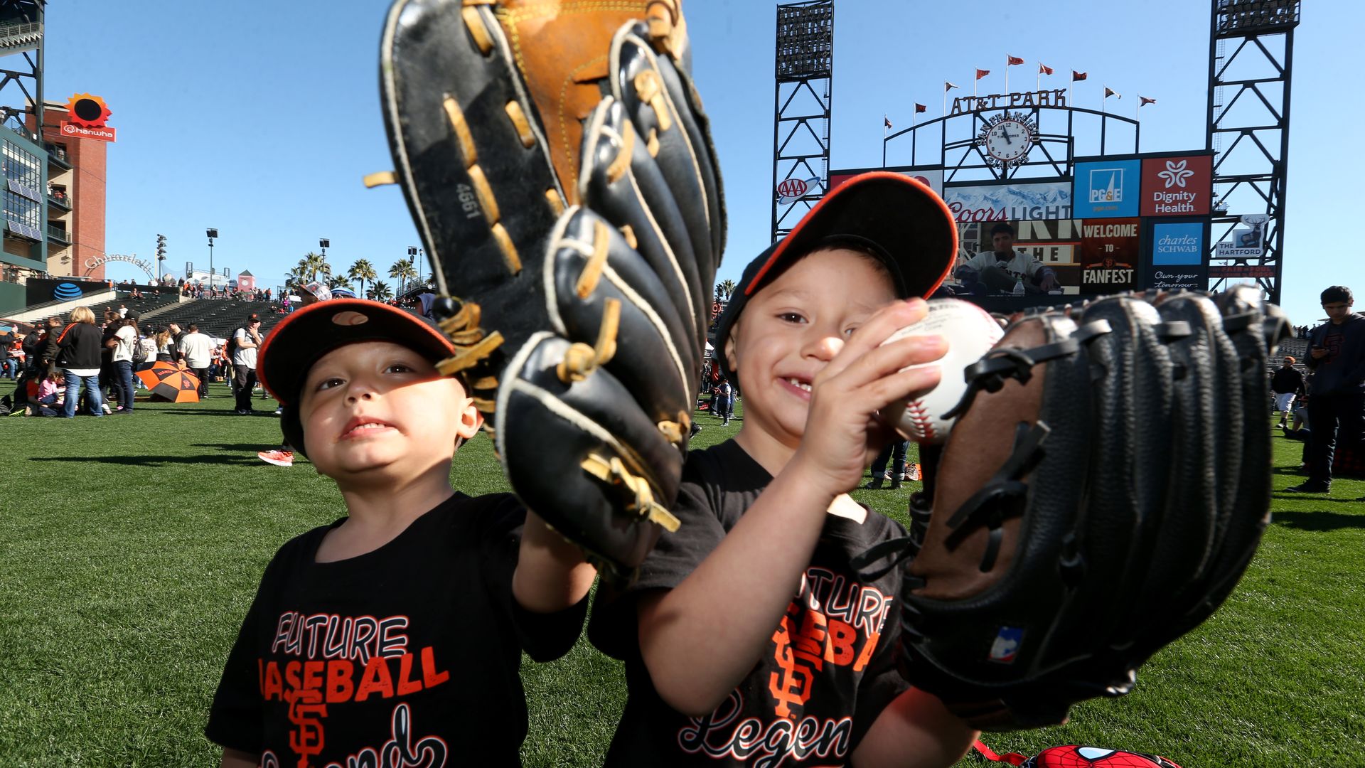 Photo of two young Giants fans raising their mitts to the camera at Oracle Park