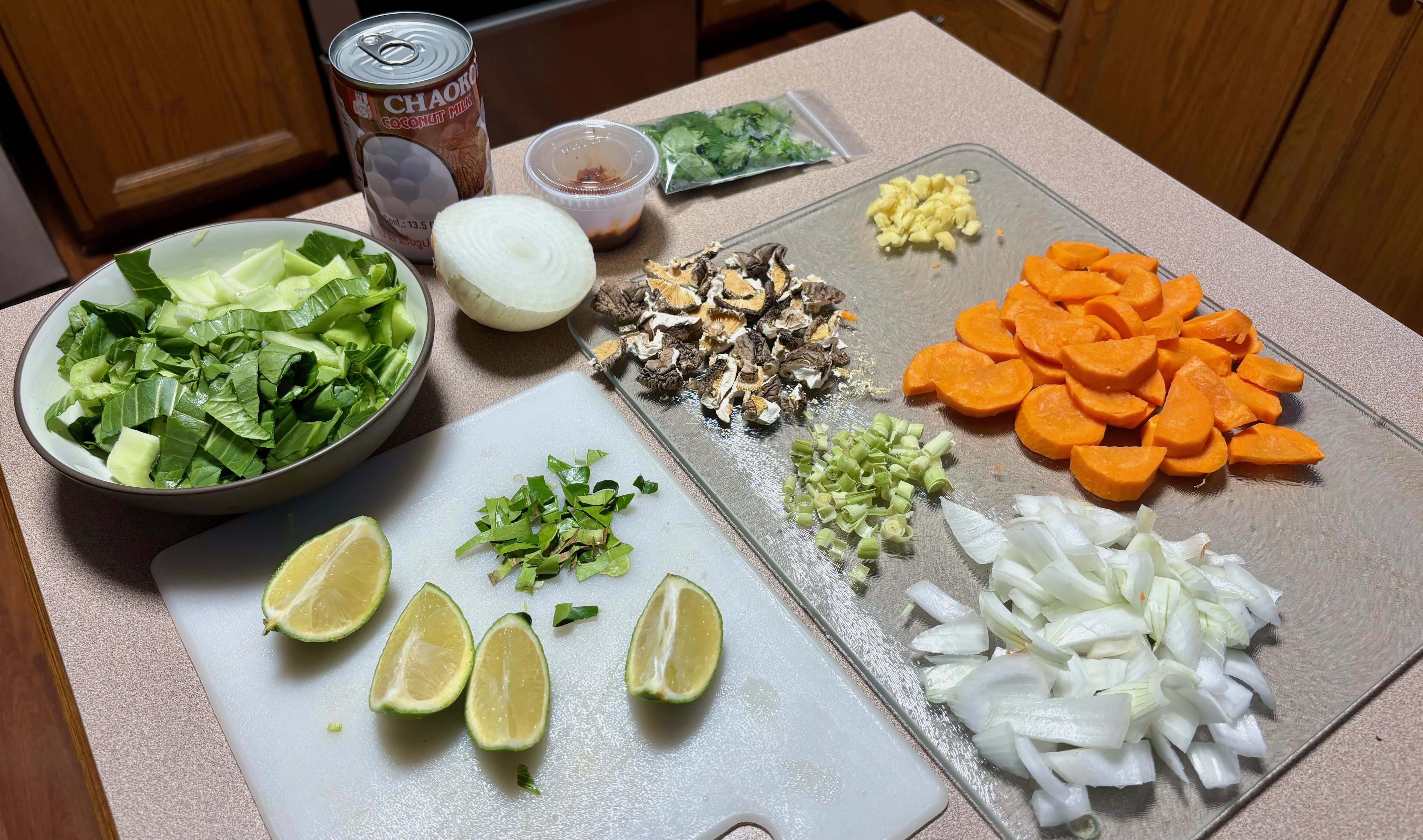 An overview of many different chopped vegetables on a counter, including carrots, onions and mushrooms, and a lime cut into wedges