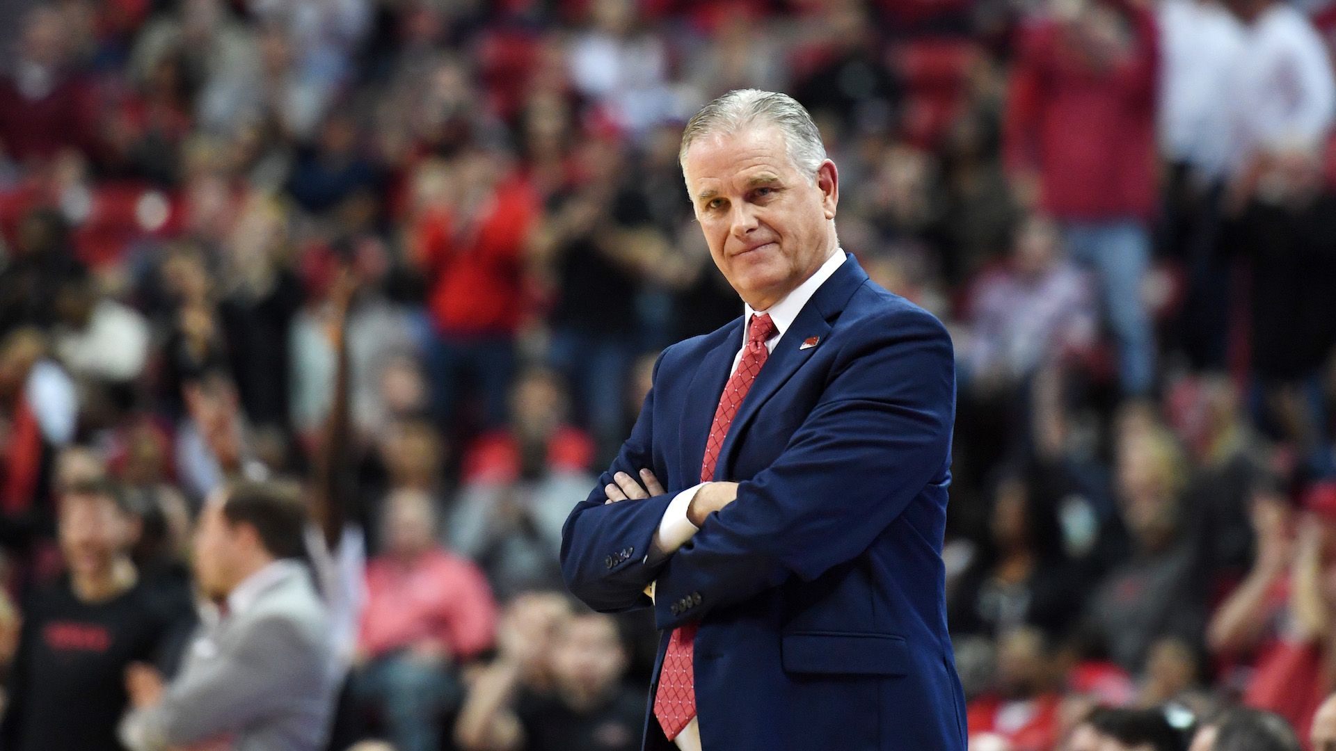 SDSU basketball coach Brian Dutcher stands with his arms crossed during a game. 