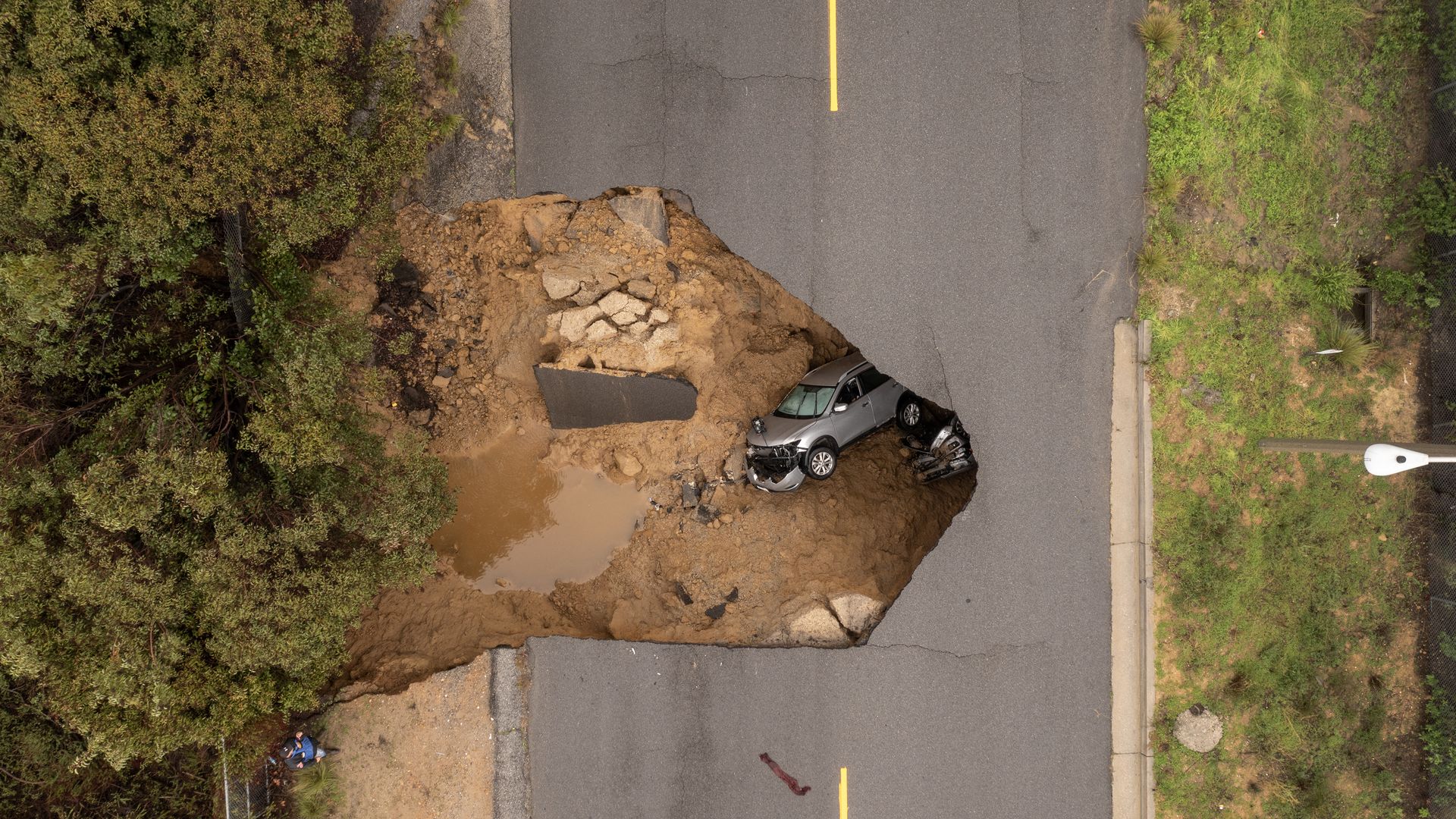 Car sits in a sinkhole created by atmospheric river storms in California.