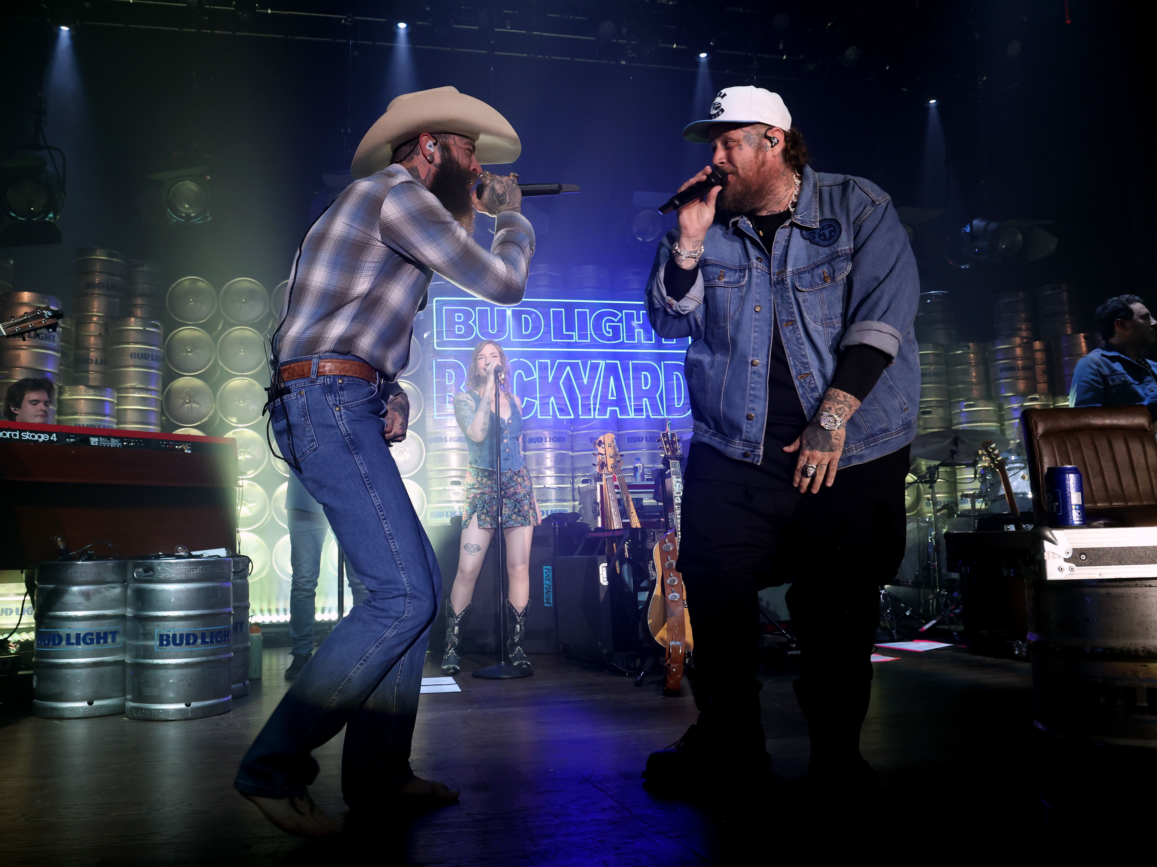 Post Malone and Jelly Roll sing onstage while looking at each other.