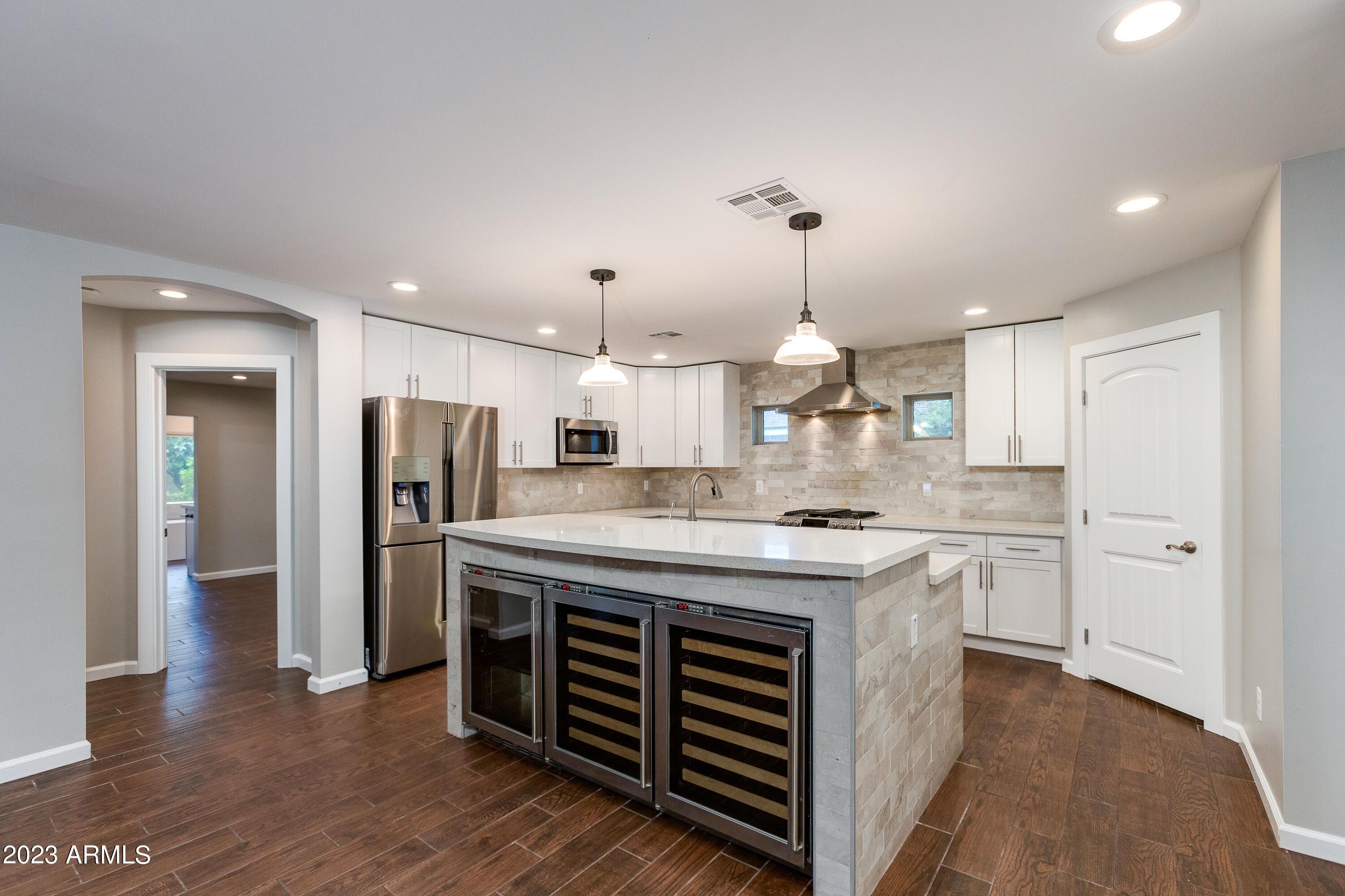 A modern kitchen with three wine fridges.