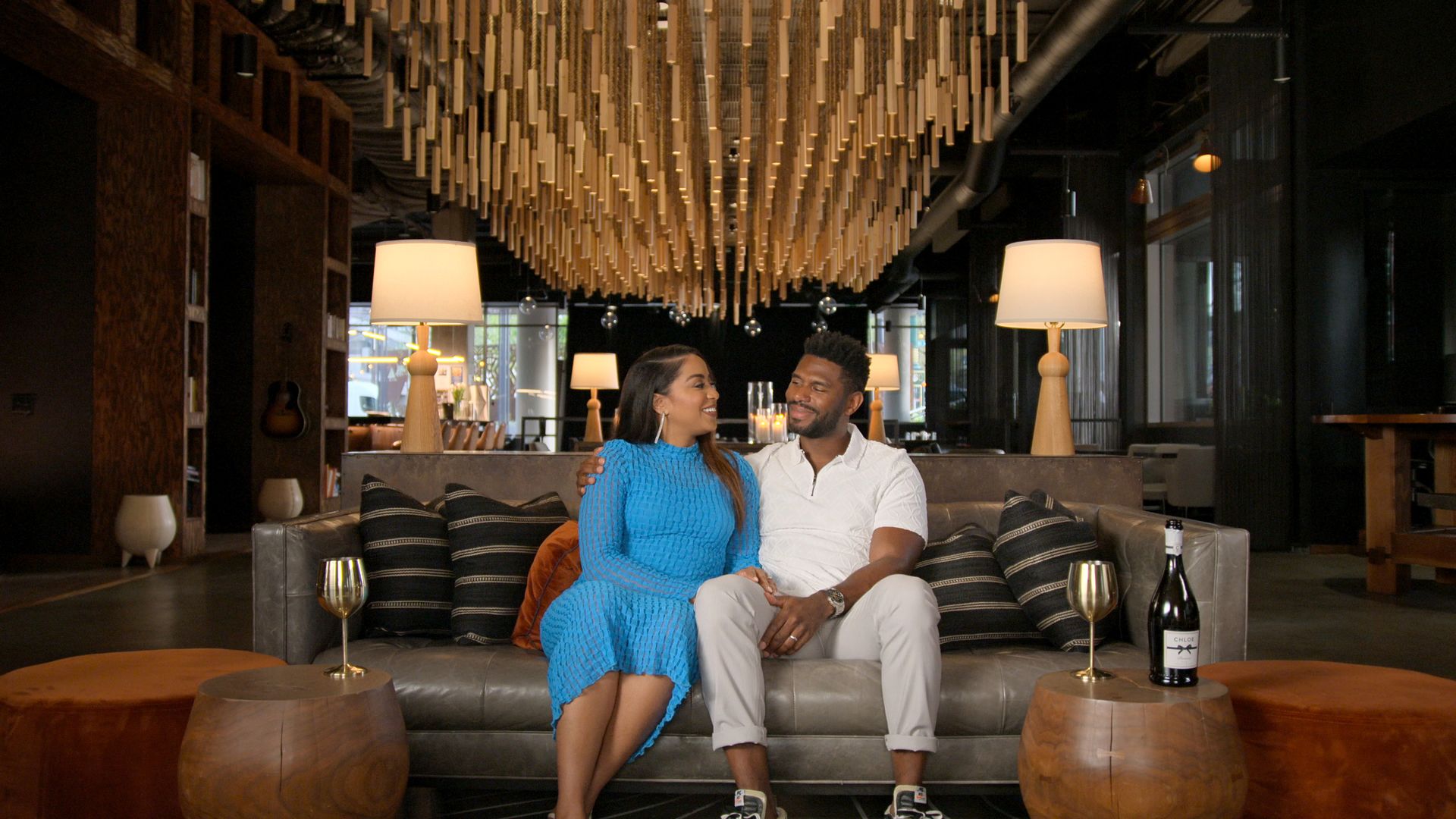 A photo of two people looking at each other and sitting on a couch.