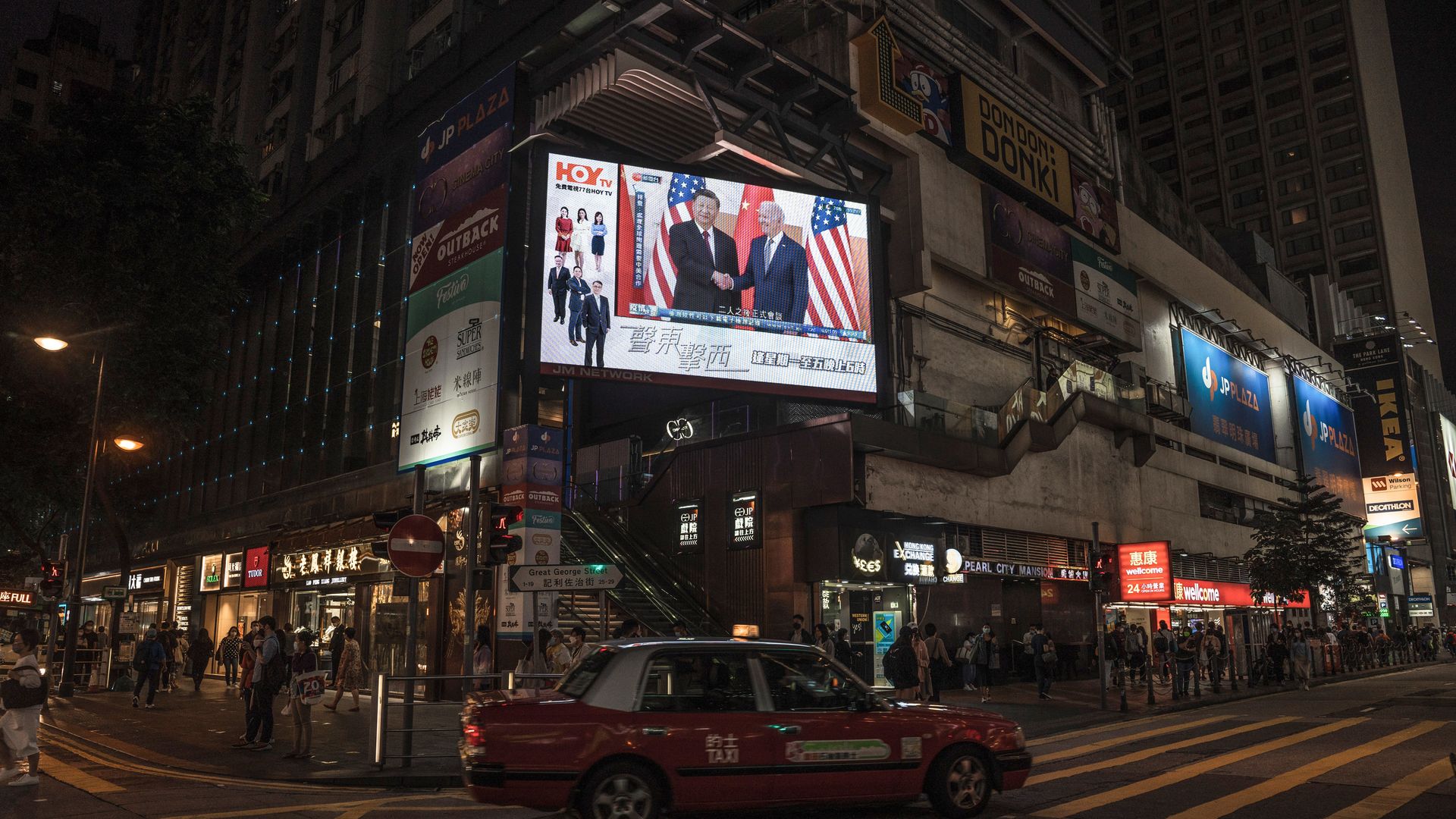 A screen on the streets of Hong Kong showing Biden and Xi shaking hands.