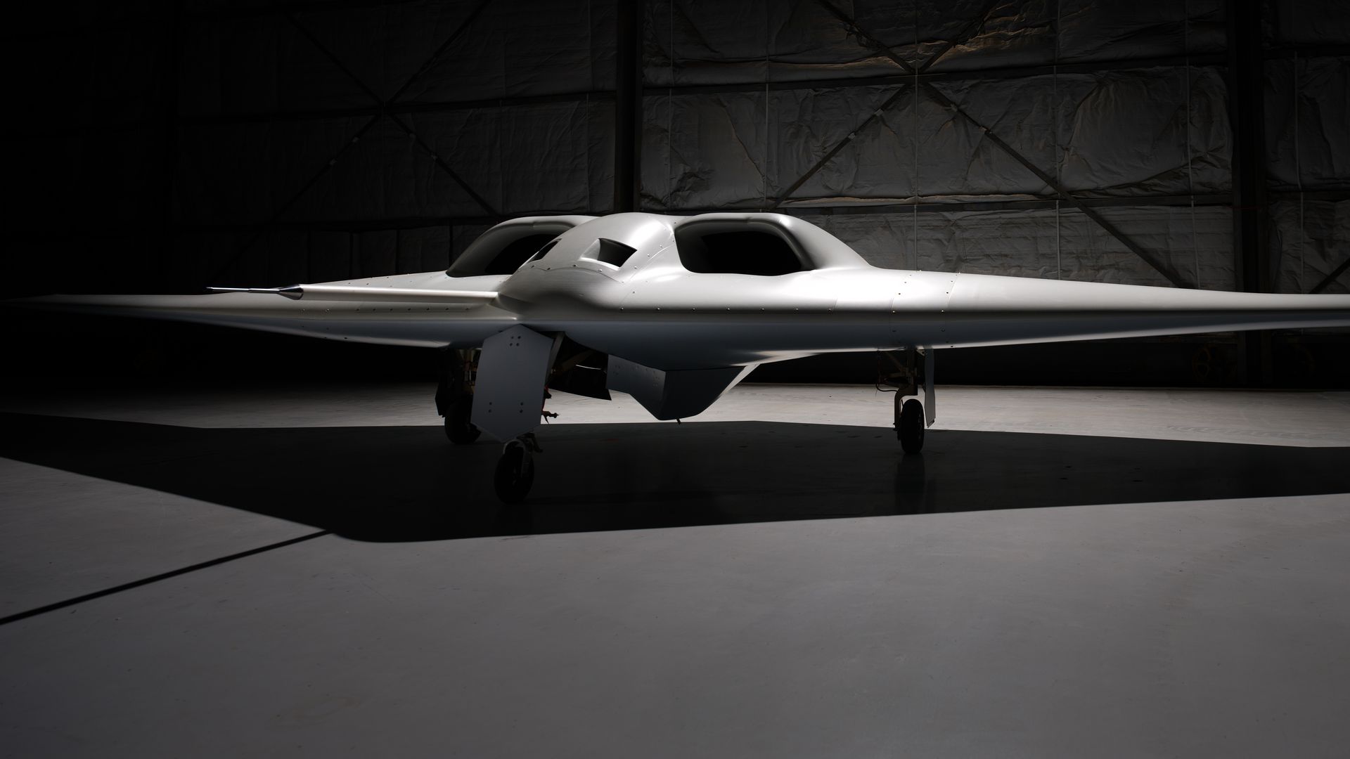 A large grey drone is seen in a darkened room. Little detail can be seen of the secretive aircraft.