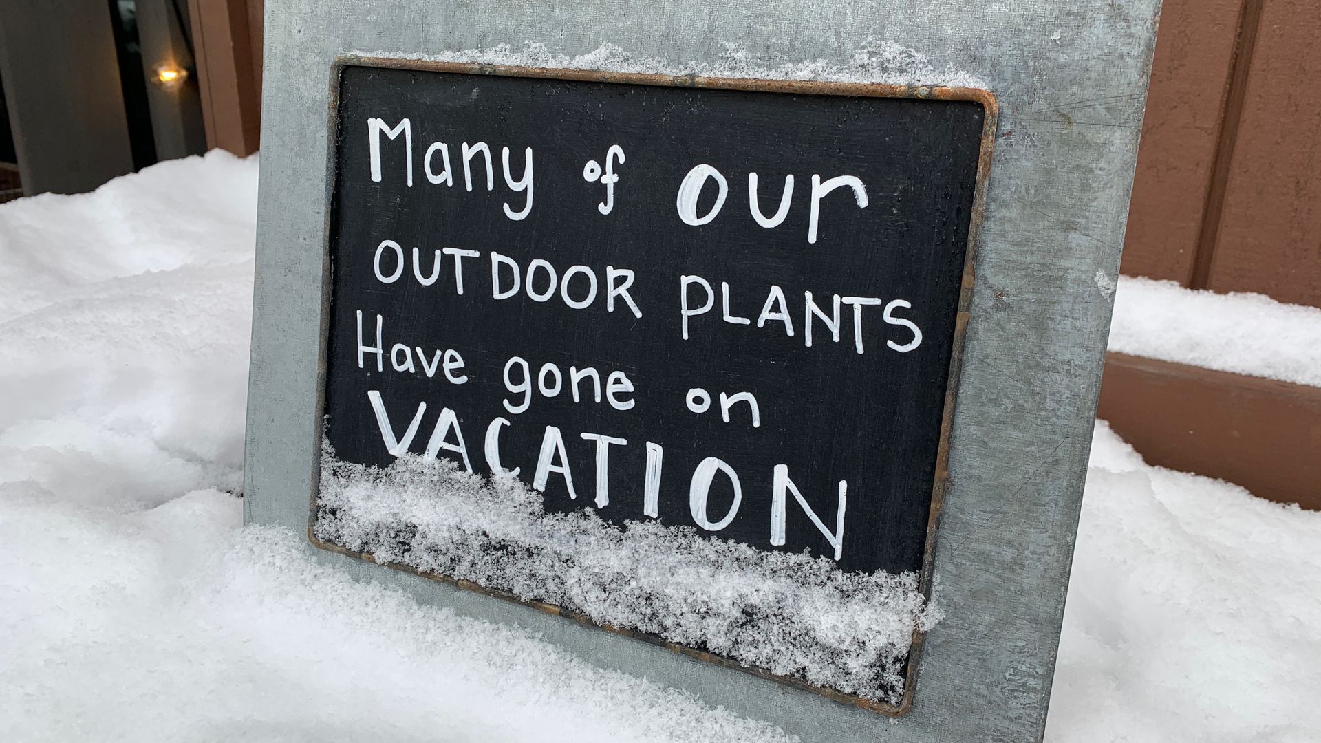 A sign outside a plant nursery says " Many of our outdoor plants have gone on vacation" 