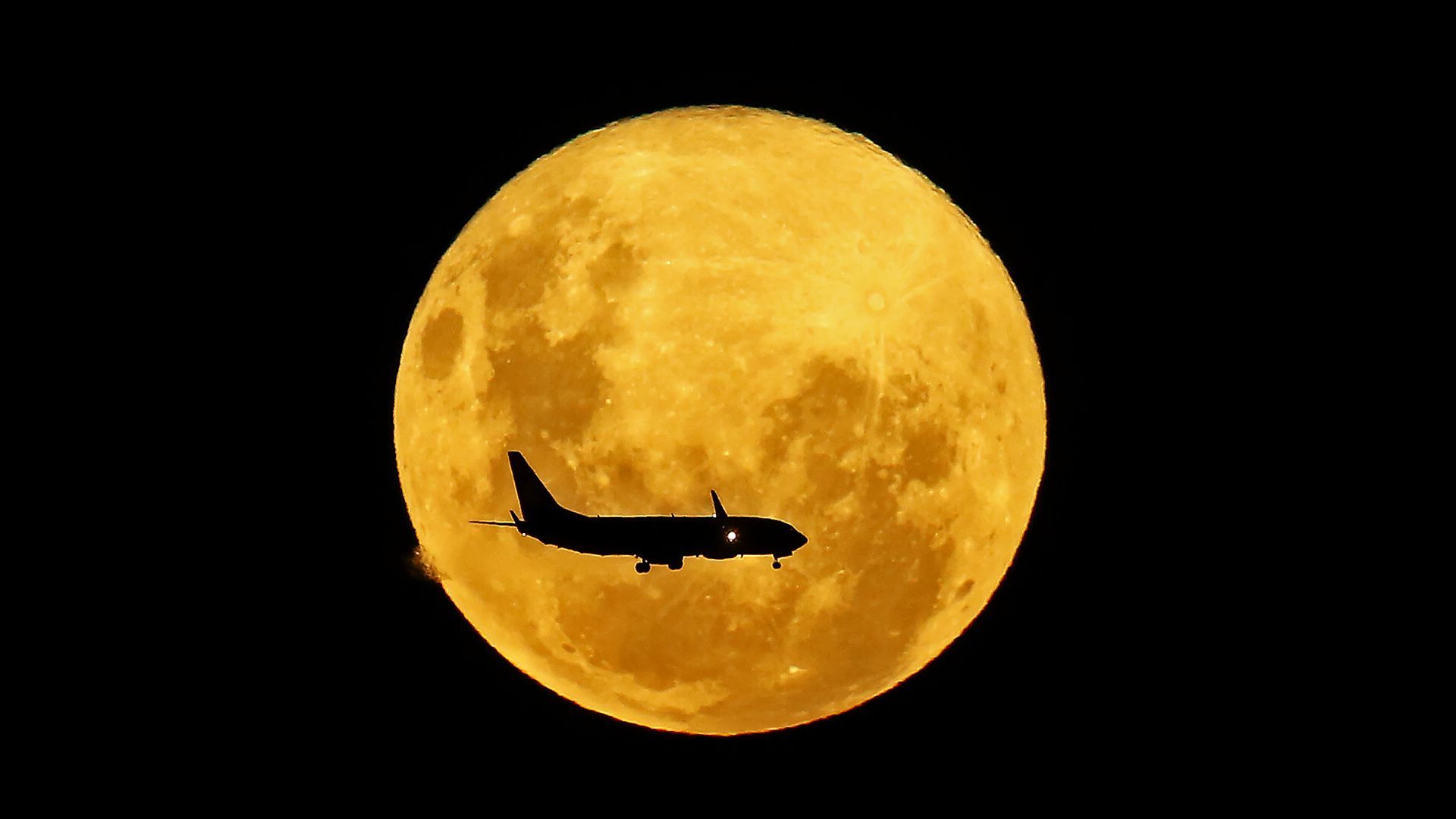 A plane passes in front of the full Moon as seen from Curitiba, Brazil. 
