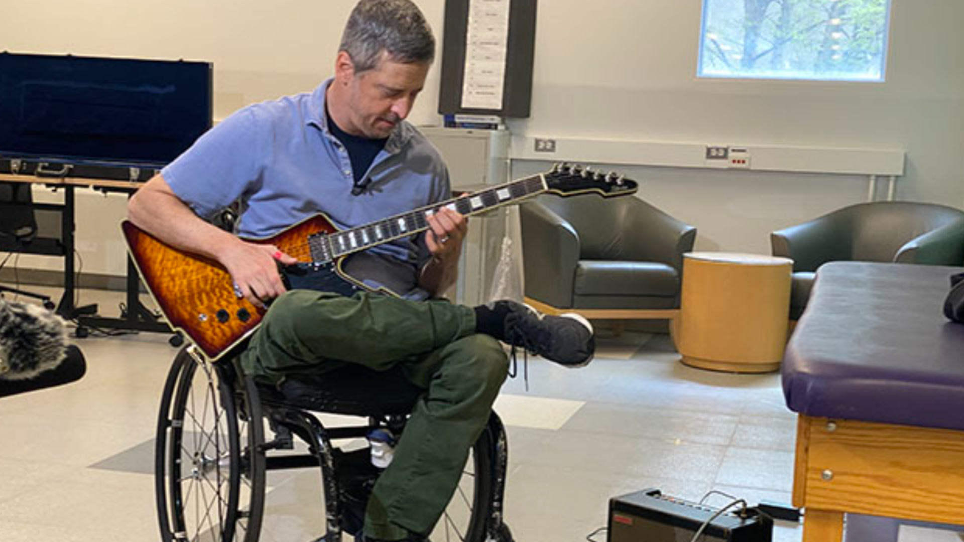 A man in a wheelchair plays a guitar. 