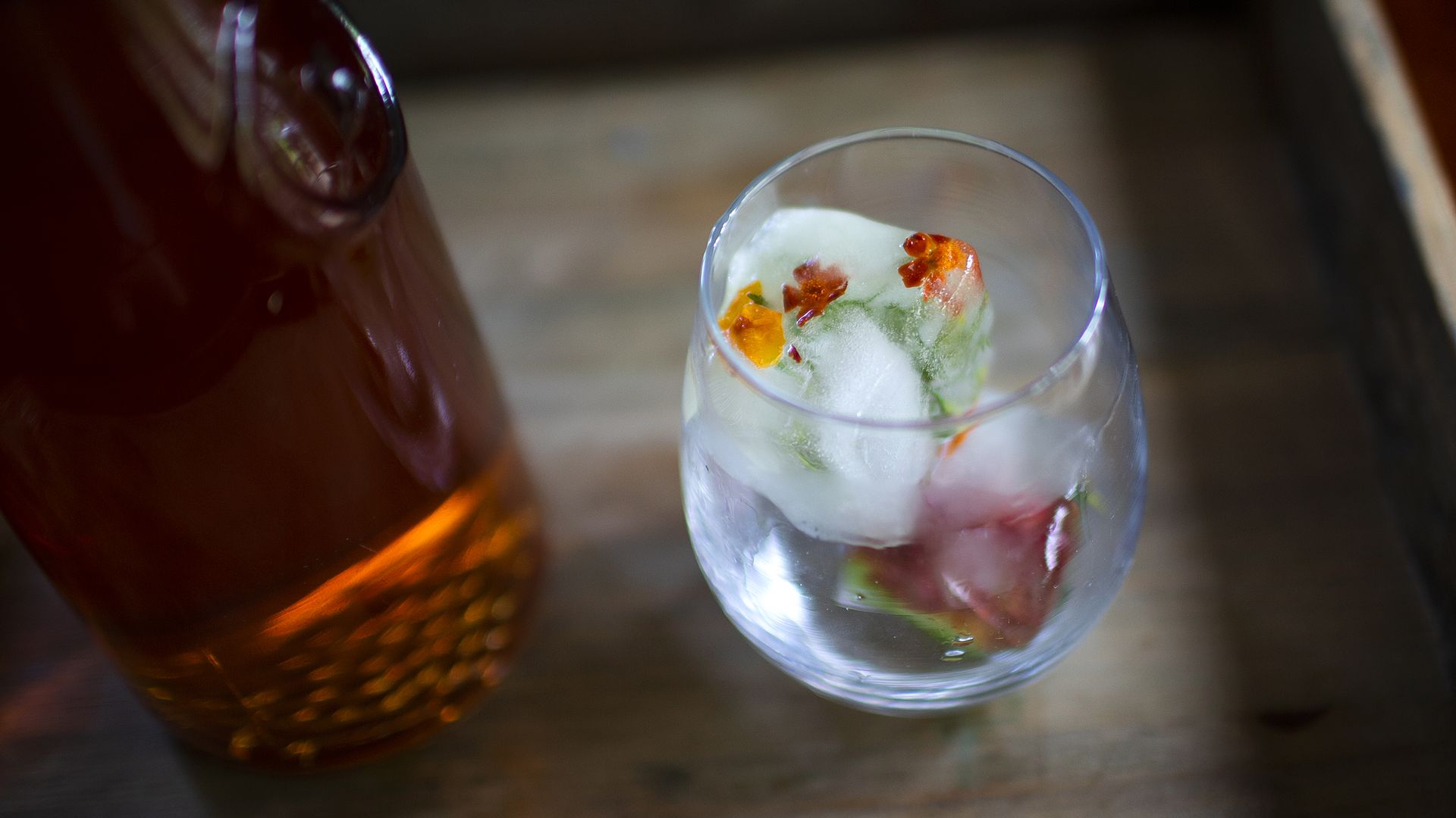 A cocktail with ice that has flowers frozen into it.