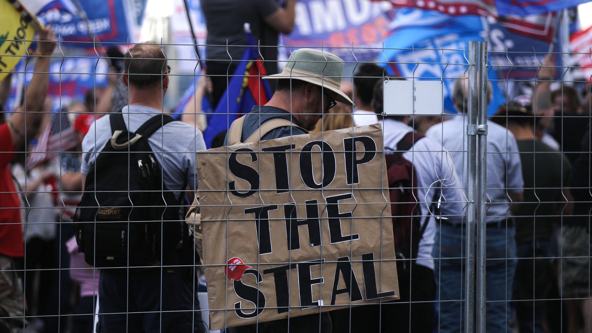 A group of protesters with a sign that says, "STOP THE STEAL." 
