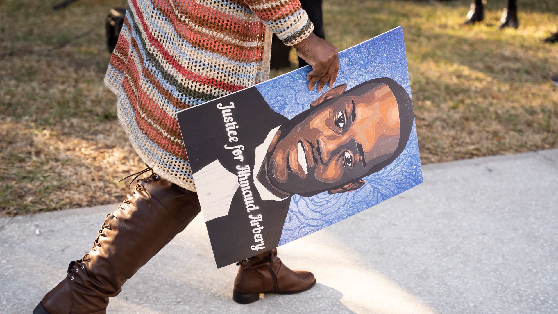 Image of person holding a sign of Ahmaud Arbery