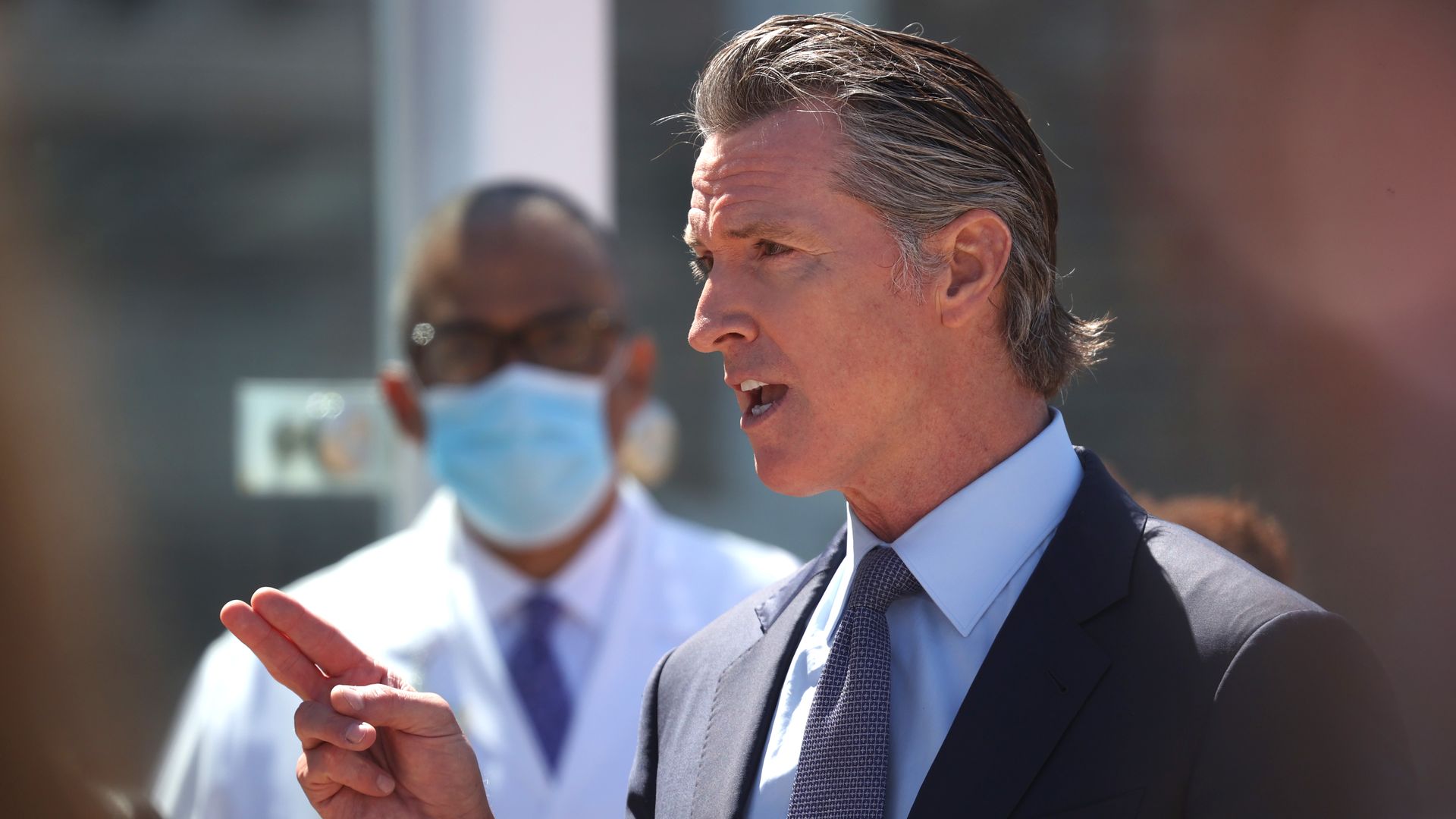 Photo of Gavin Newsom speaking and gesturing with two fingers