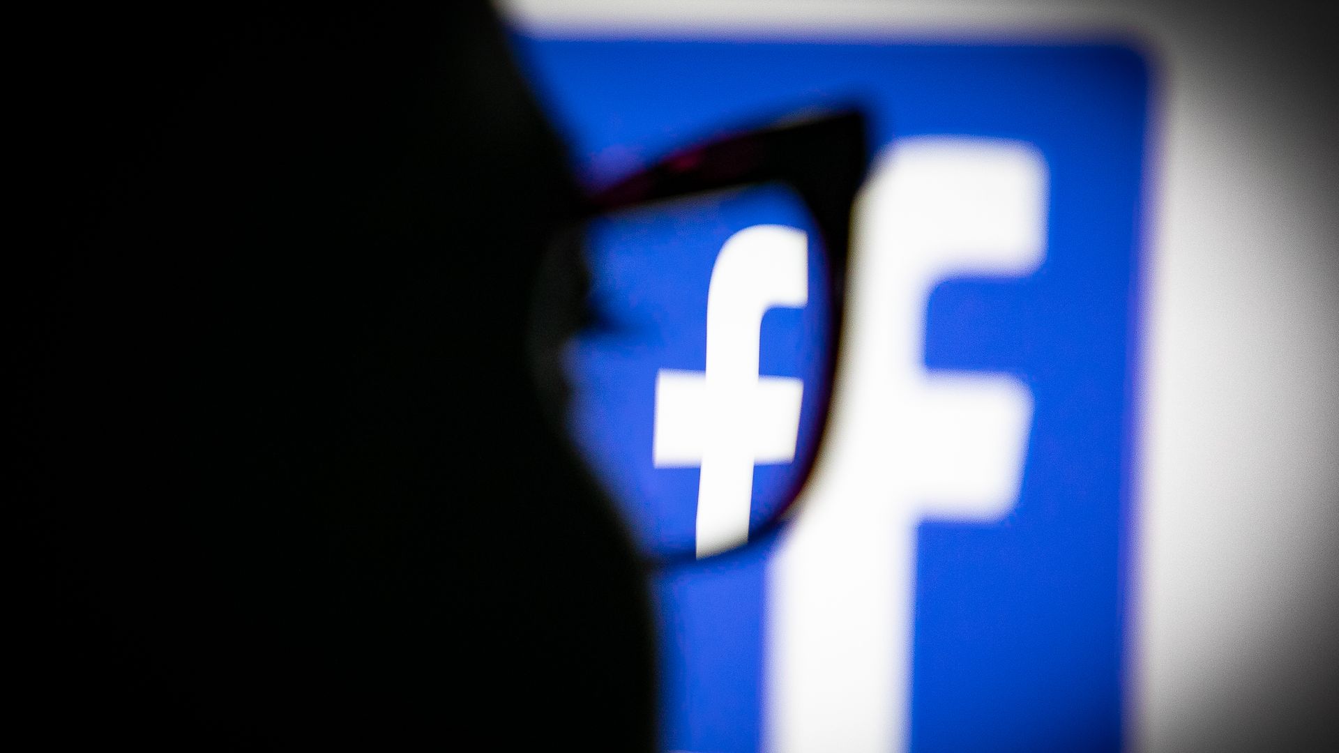 A user looks at a screen displaying the Facebook logo.