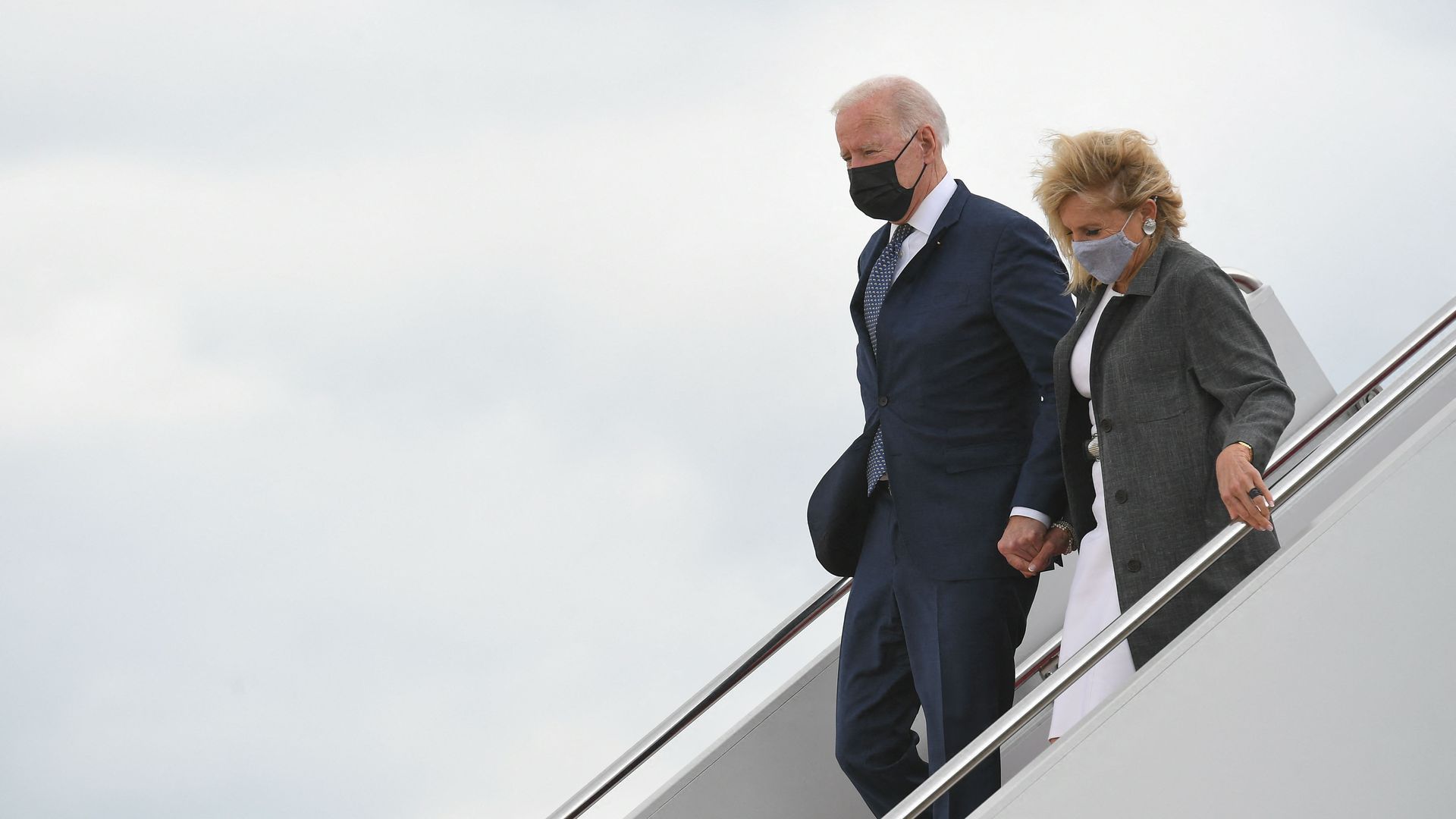 Photo of Joe and Jill Biden holding hands while walking down a staircase from the airplane