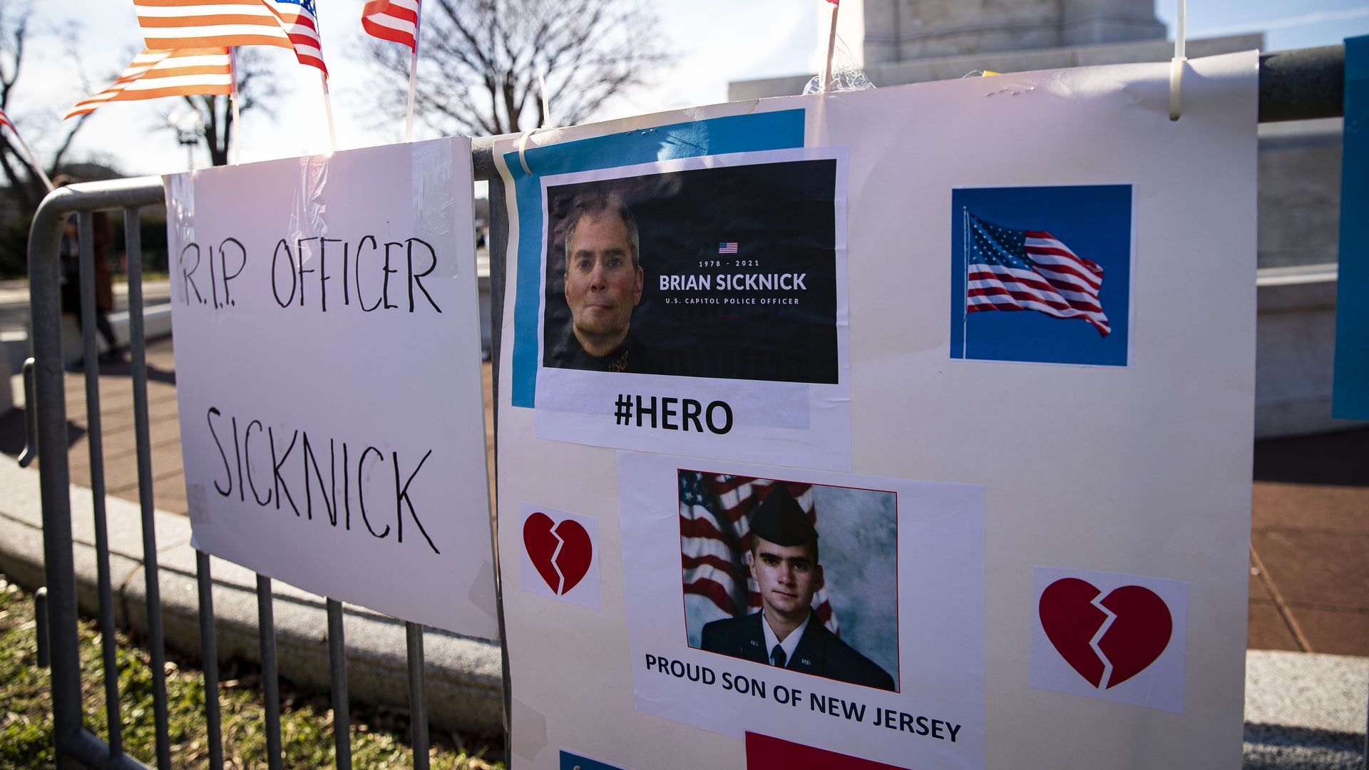 Photo of signs and American flags honoring Brian Sicknick displayed near the Capitol