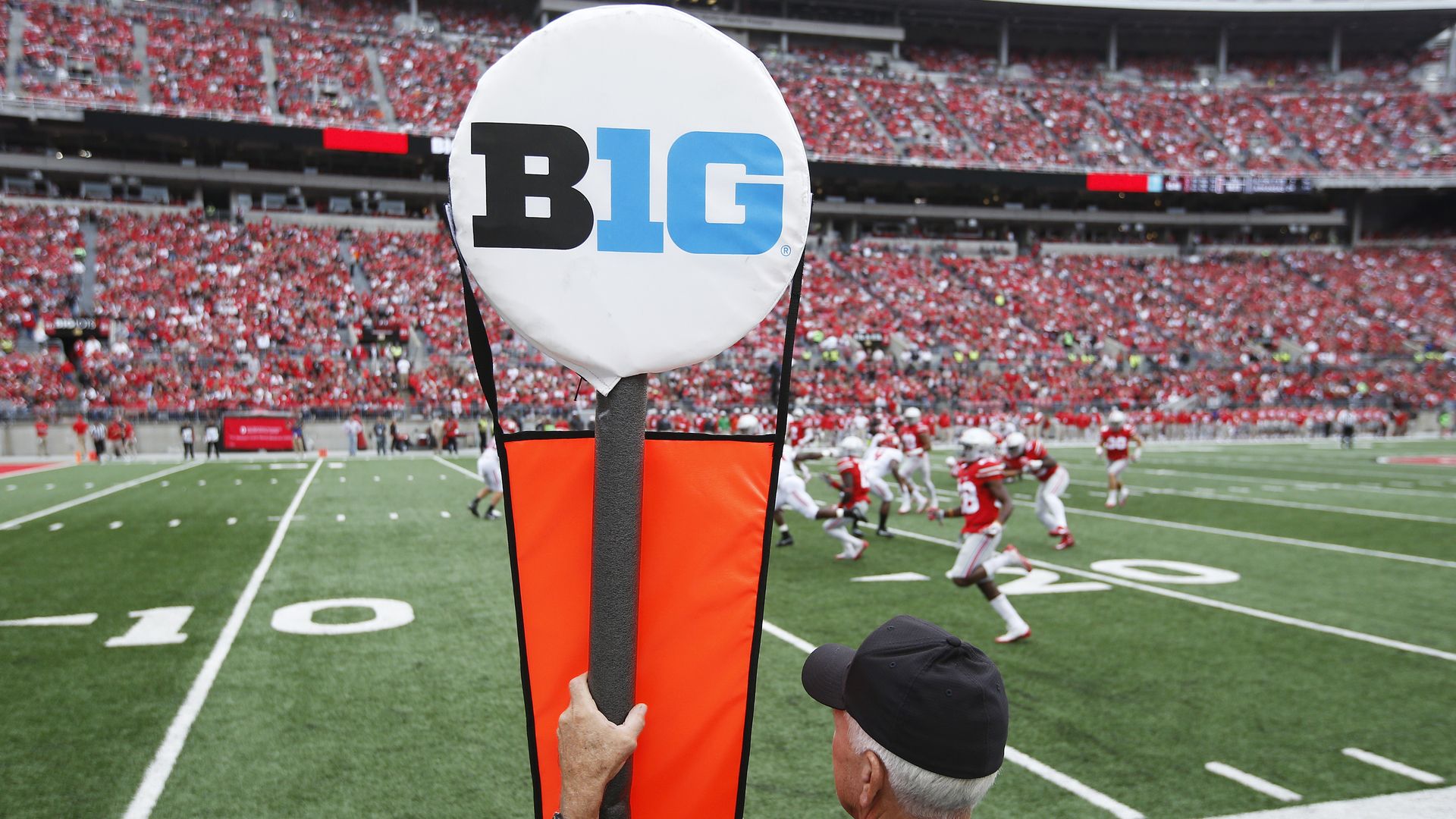 The big ten logo on a marker on the sideline of a football field. 