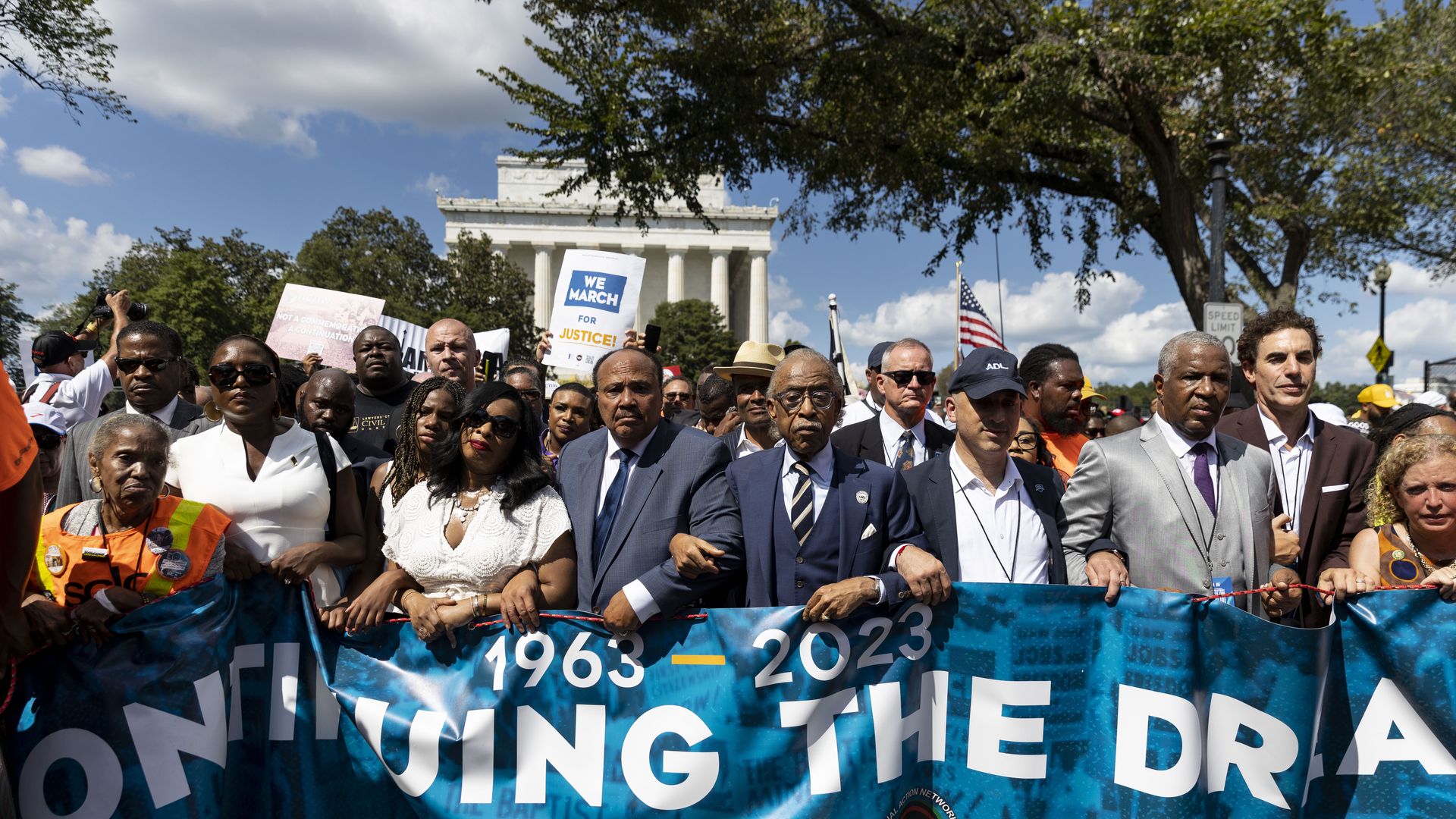 Rev. Al Sharpton, Martin Luther King III, his wife Arndrea Waters King, Yolanda Renee King, 15-year old granddaughter of the Rev. Martin Luther King Jr., and actor Sacha Baron Cohen carry a banner as demonstrators march on the 60th anniversary of the March on Washington on August 26, 2023.