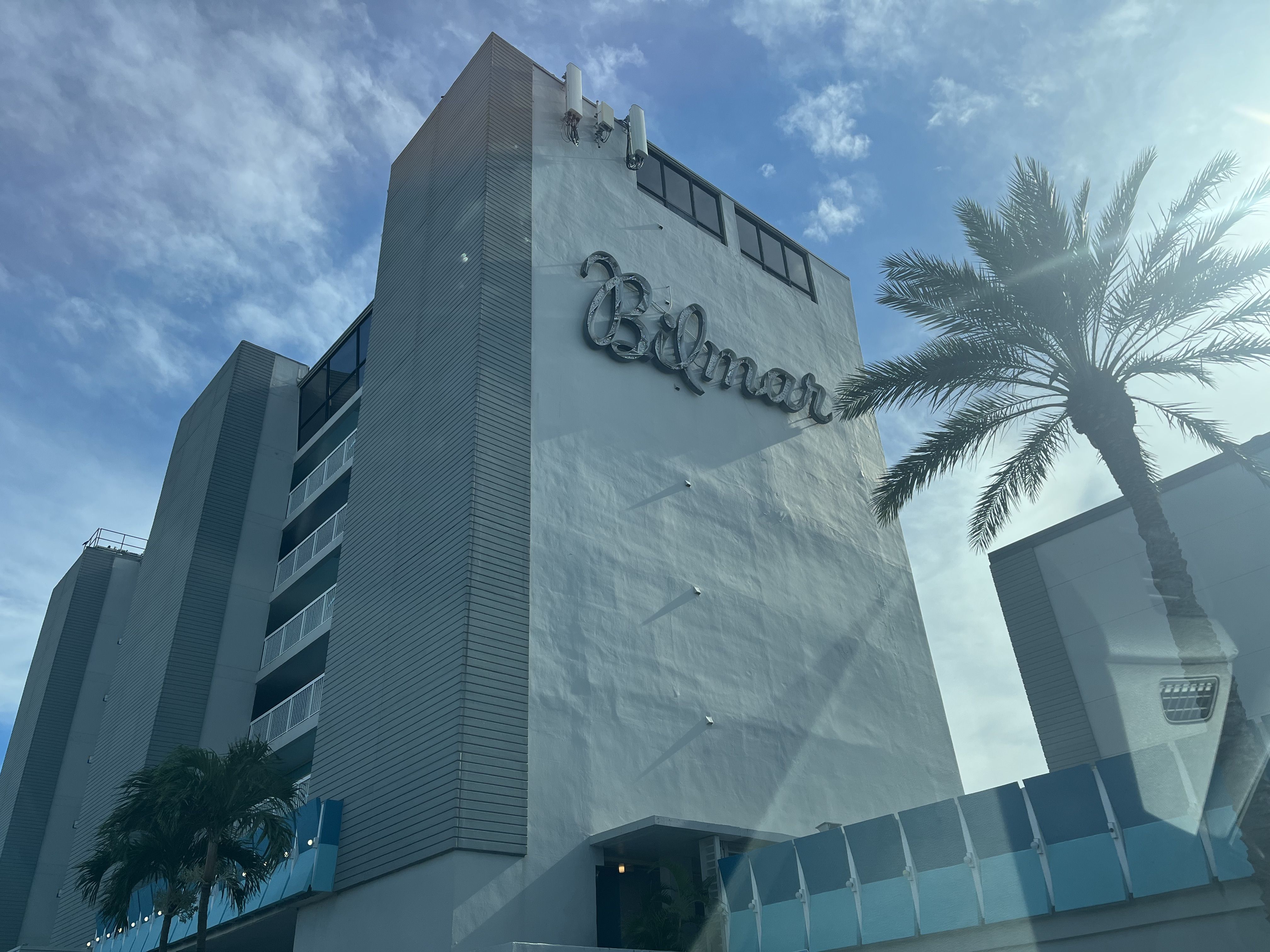 A tall cream-colored building with a neon sign that reads "Bilmar" in loopy cursive. 