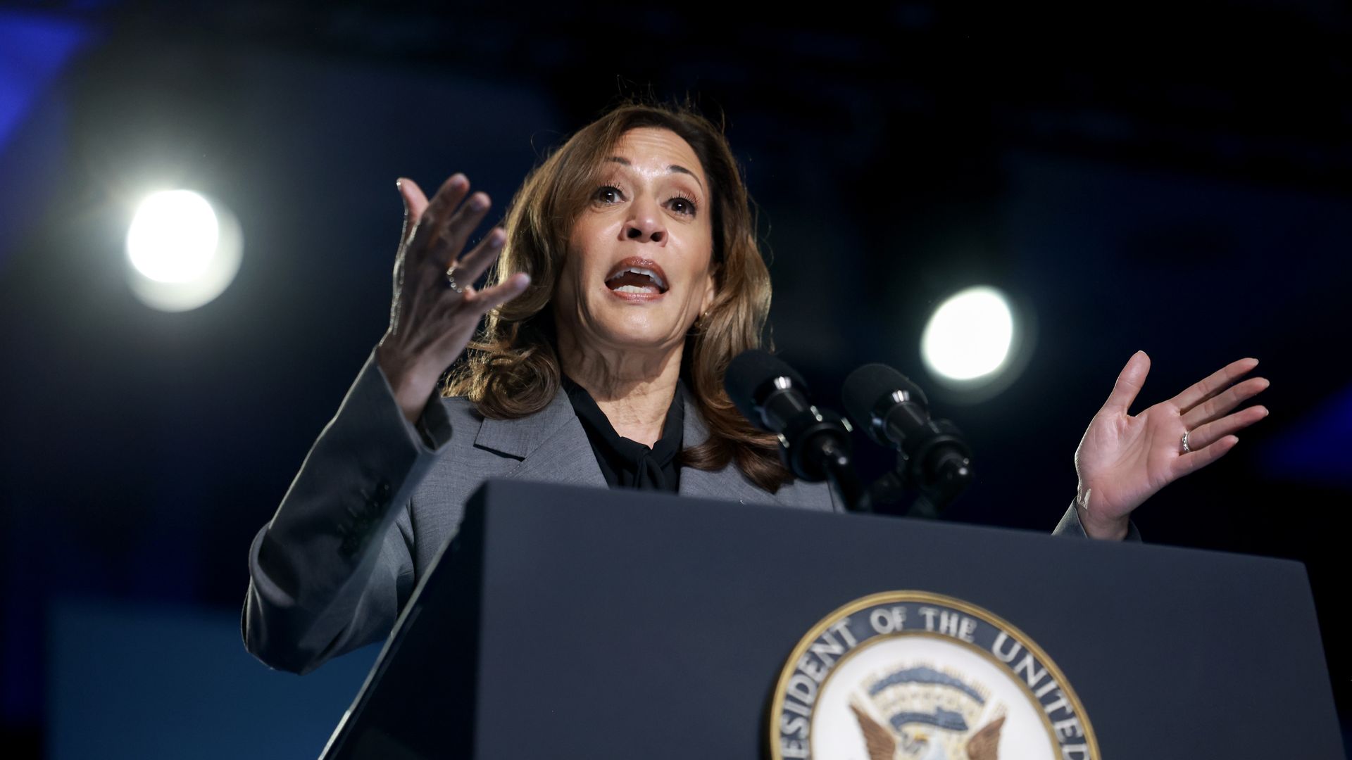 Kamala Harris speaks behind a blue lecturn with the vice president's seal.