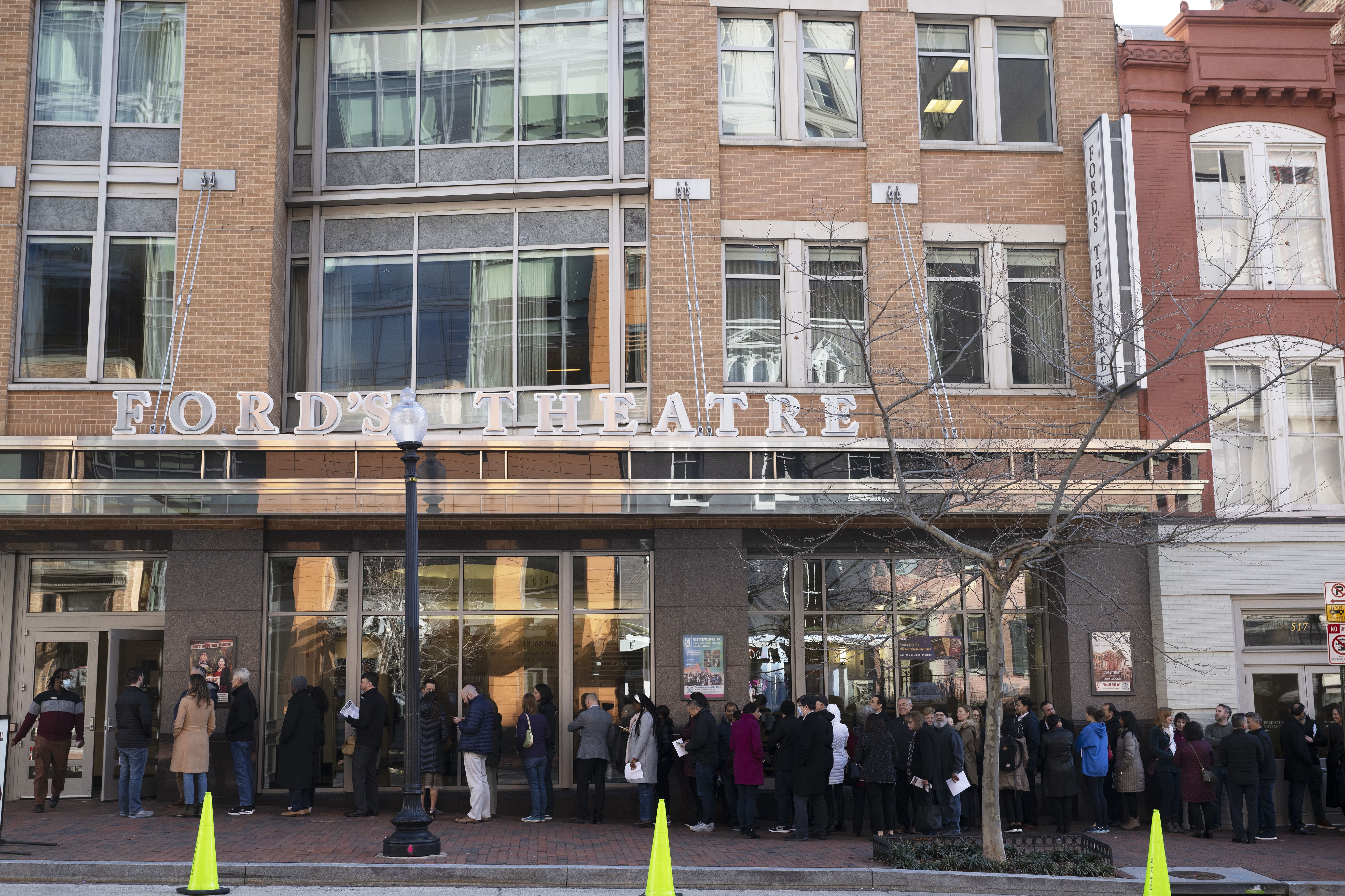 A line of people outside a brick building with "Ford's Theatre" in silver lettering.