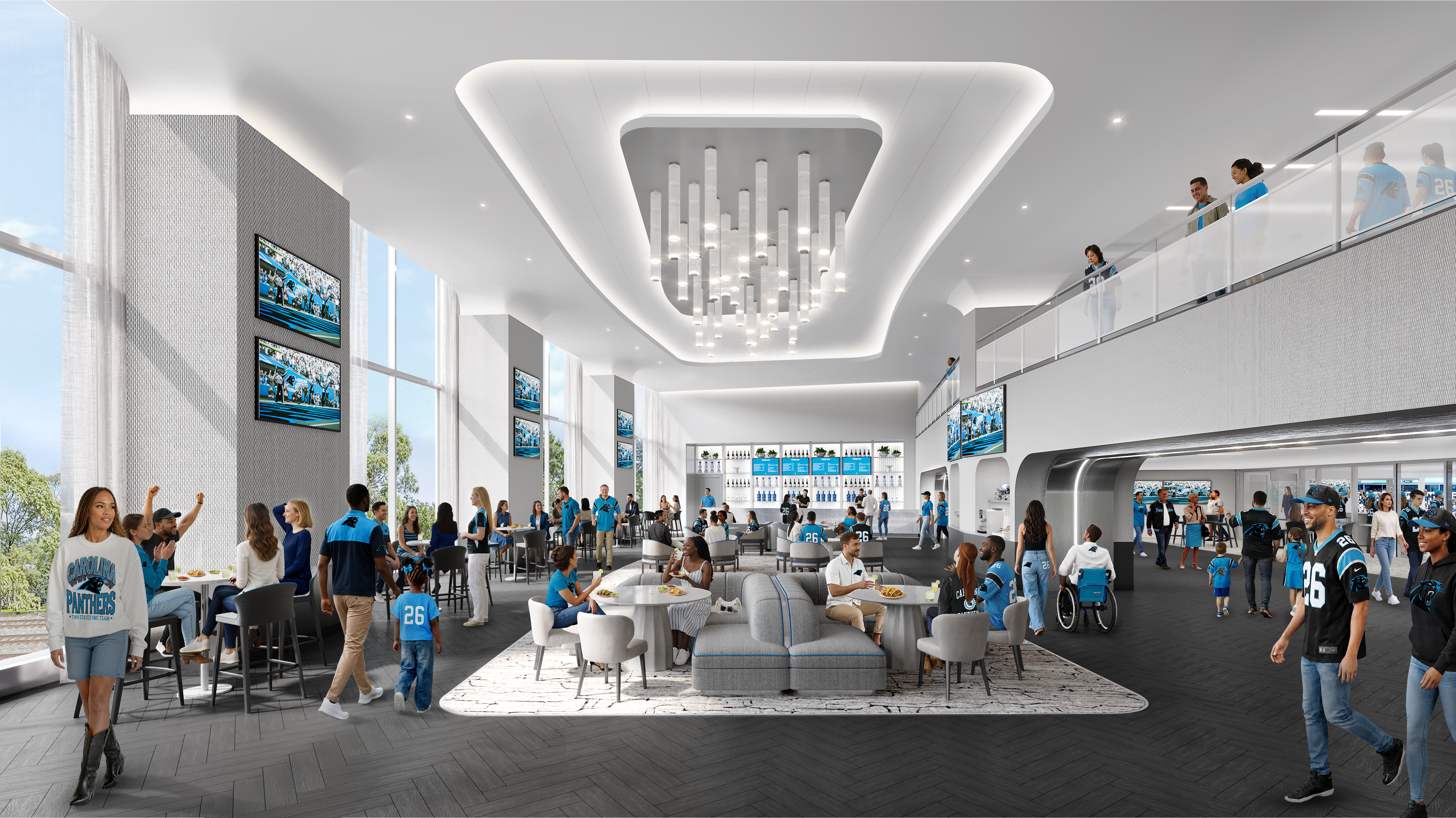 Wide view of a modern stadium concourse filled with Carolina Panthers fans in blue jerseys. A sculpted white ceiling with a central chandelier, glass balcony, screens, and lounge seating around tables.