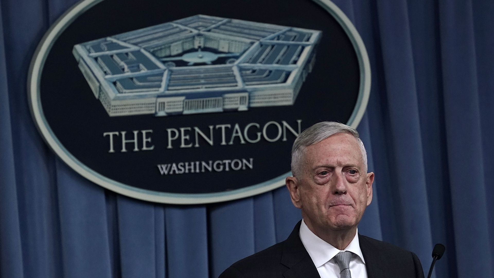 Defense Secretary Mattis stands in front of Pentagon sign. 