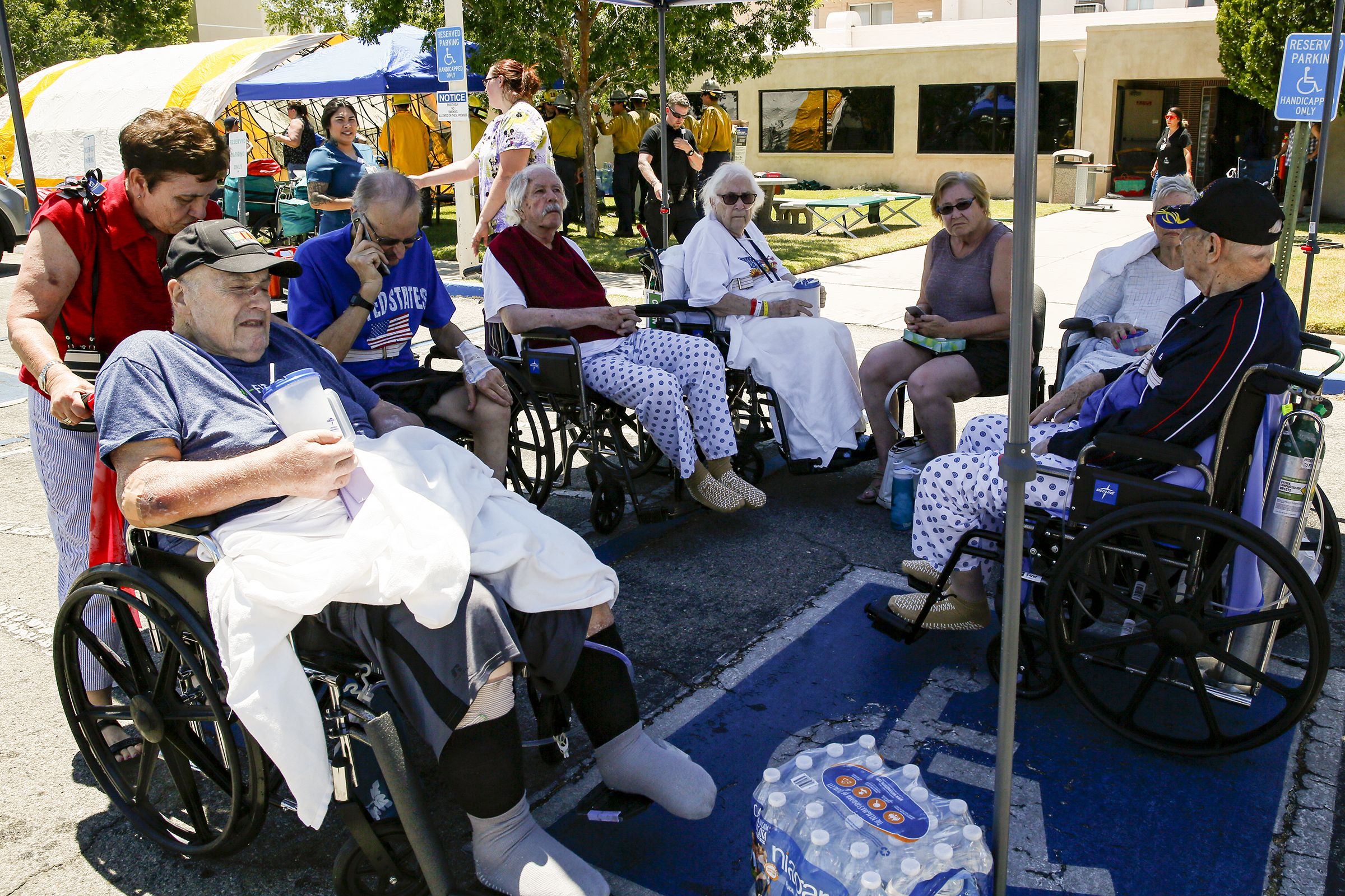 This image shows a circle of seniors in wheelchairs in a shaded area, sitting outside.