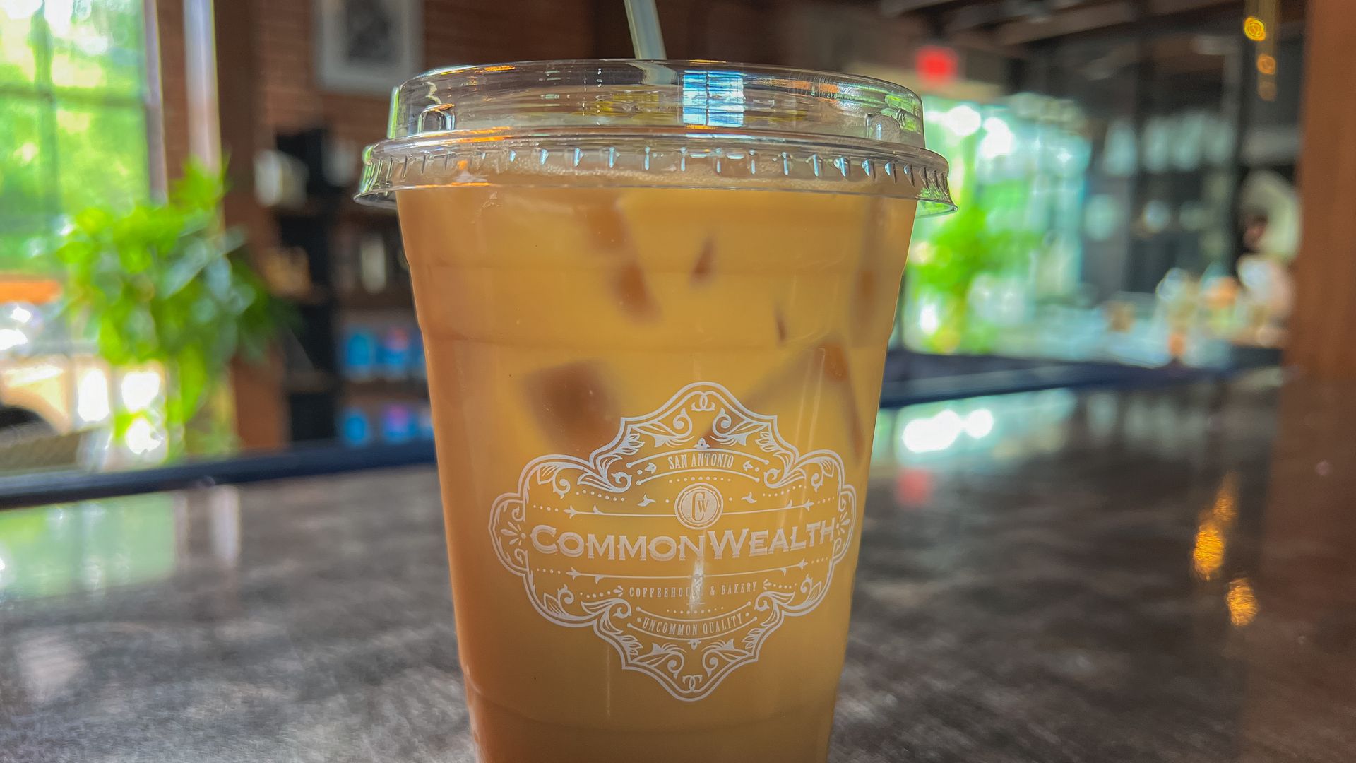 A plastic cup of light iced coffee with a straw.