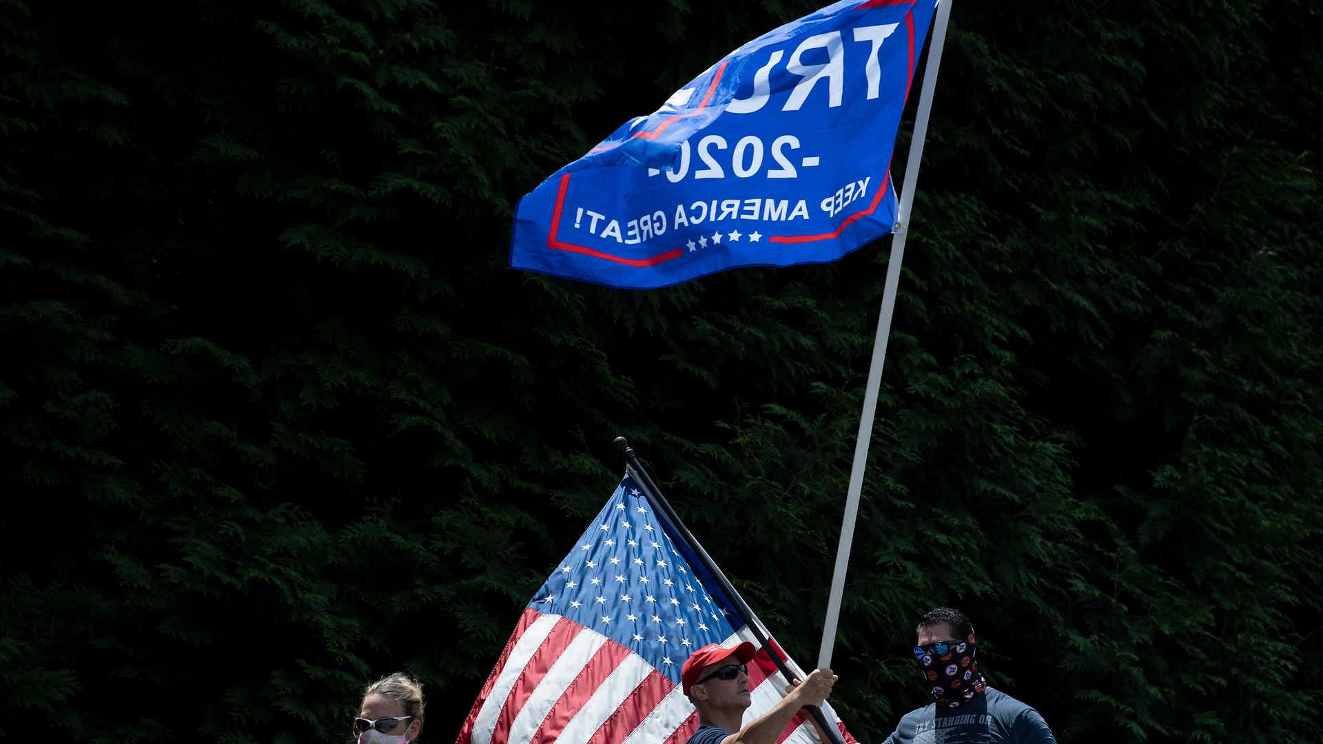 President Trump supporters waving a Trump flag and holding signs outdoors