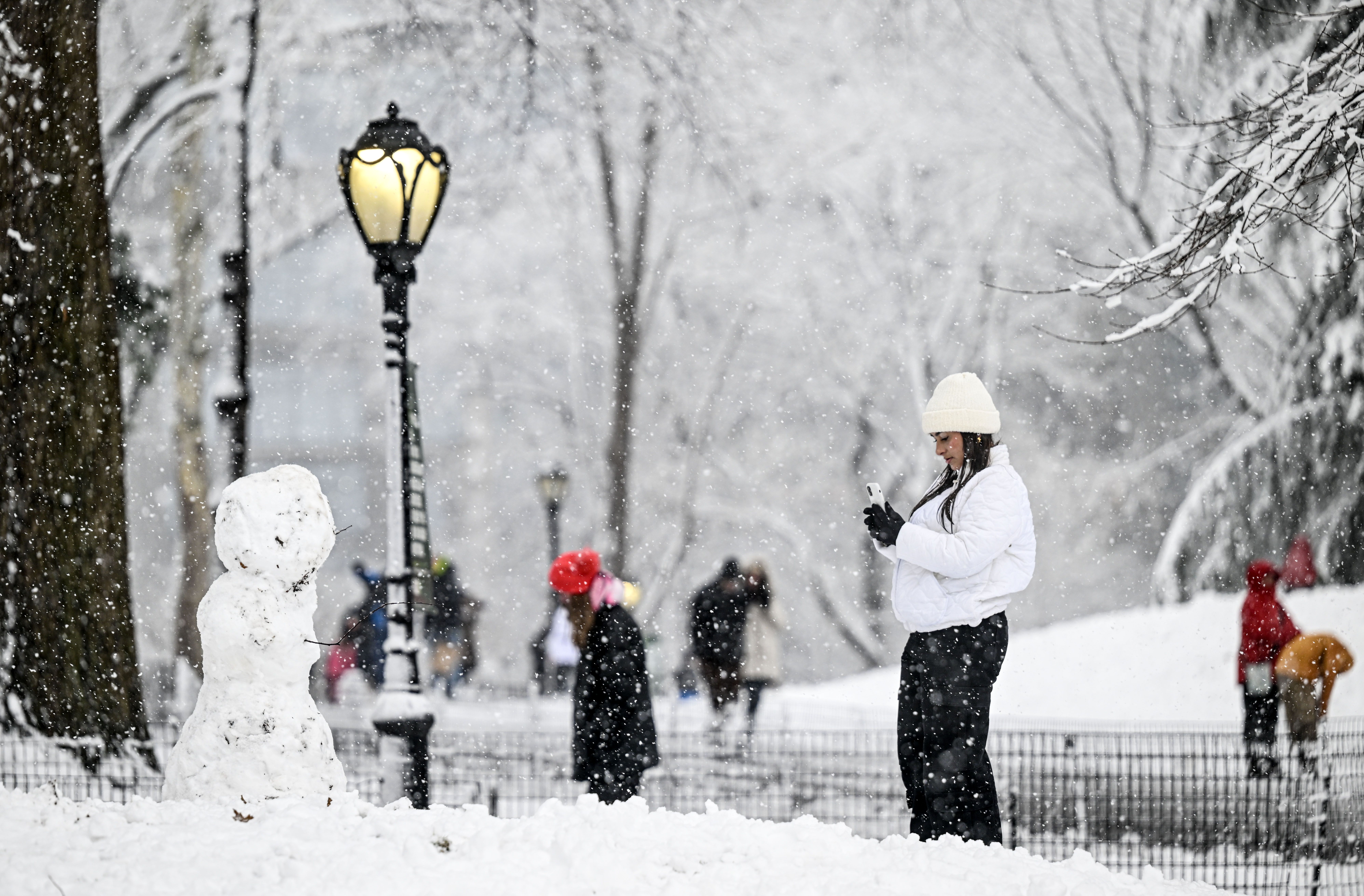 A person taking a photo of a snowman in Central Park on Feb. 13