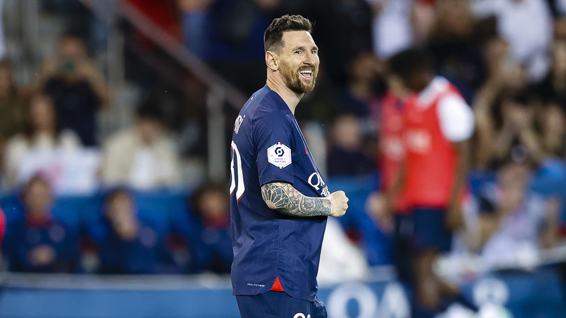 Lionel Messi laughs while lightly tugging his jersey at a soccer game