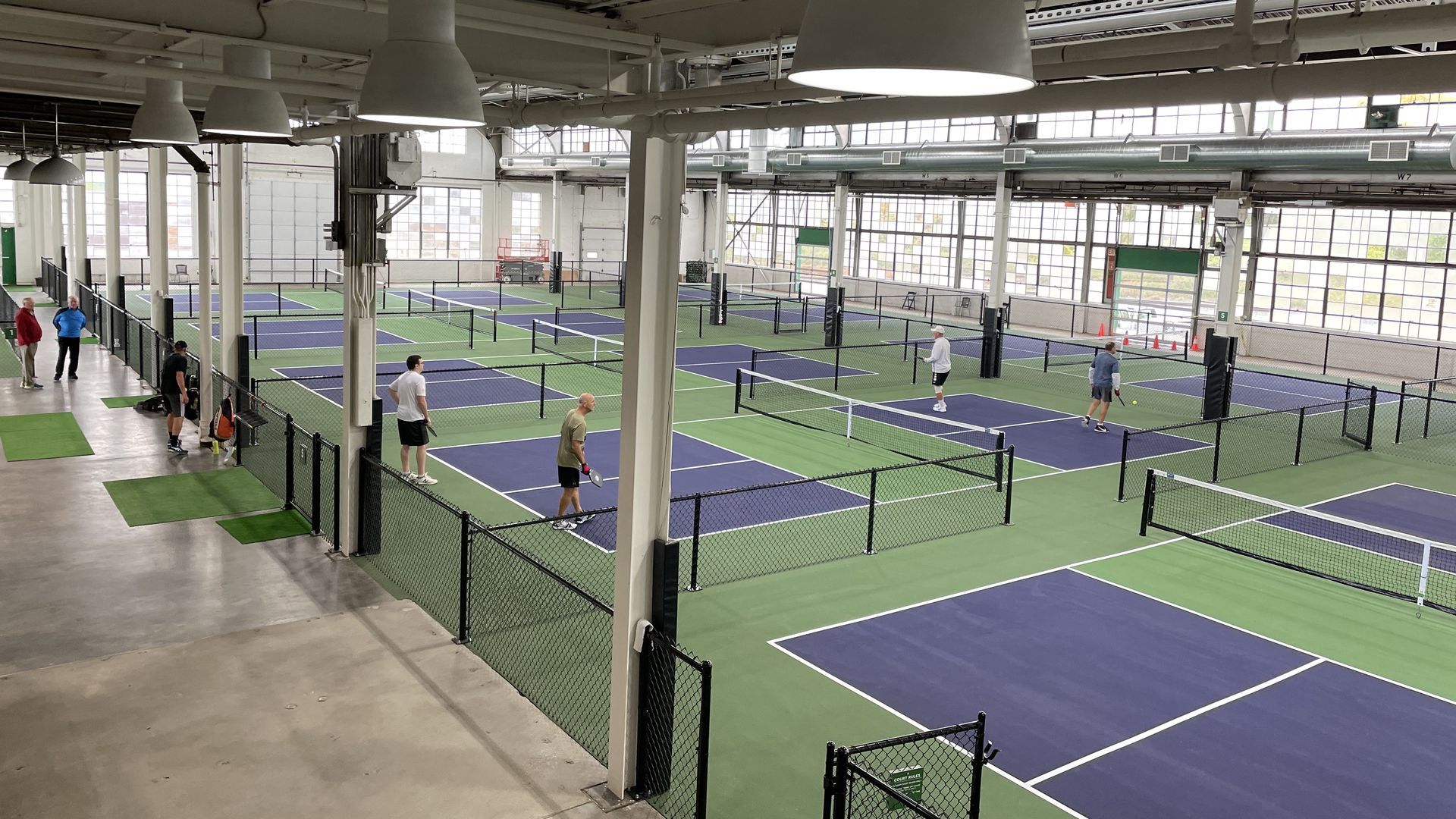 Groups of people play pickleball on pickleball courts