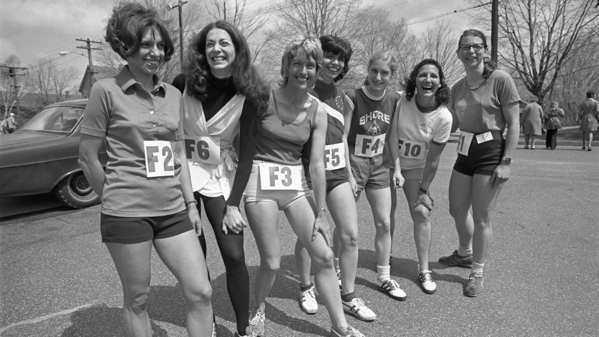 A black and white photo of seven female runners standing in a line