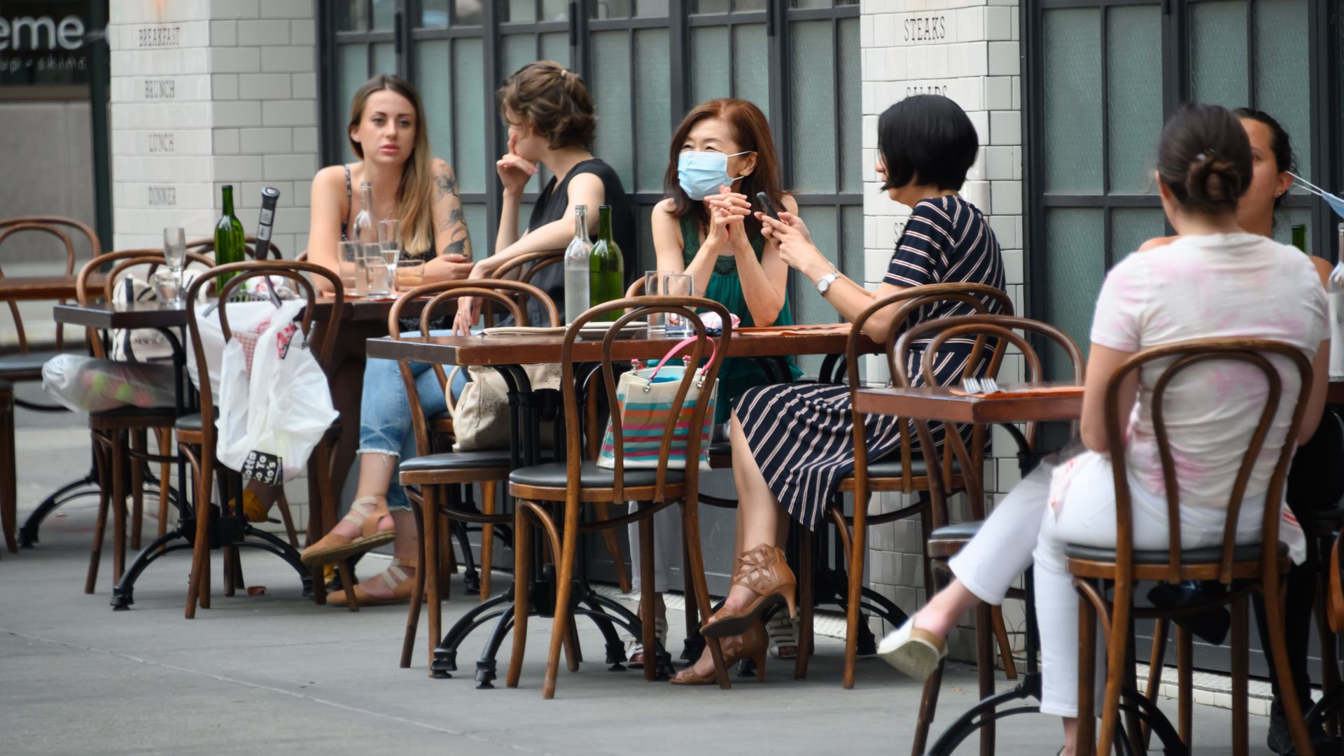 People sit outside a restaurant in New York City on June 30. 