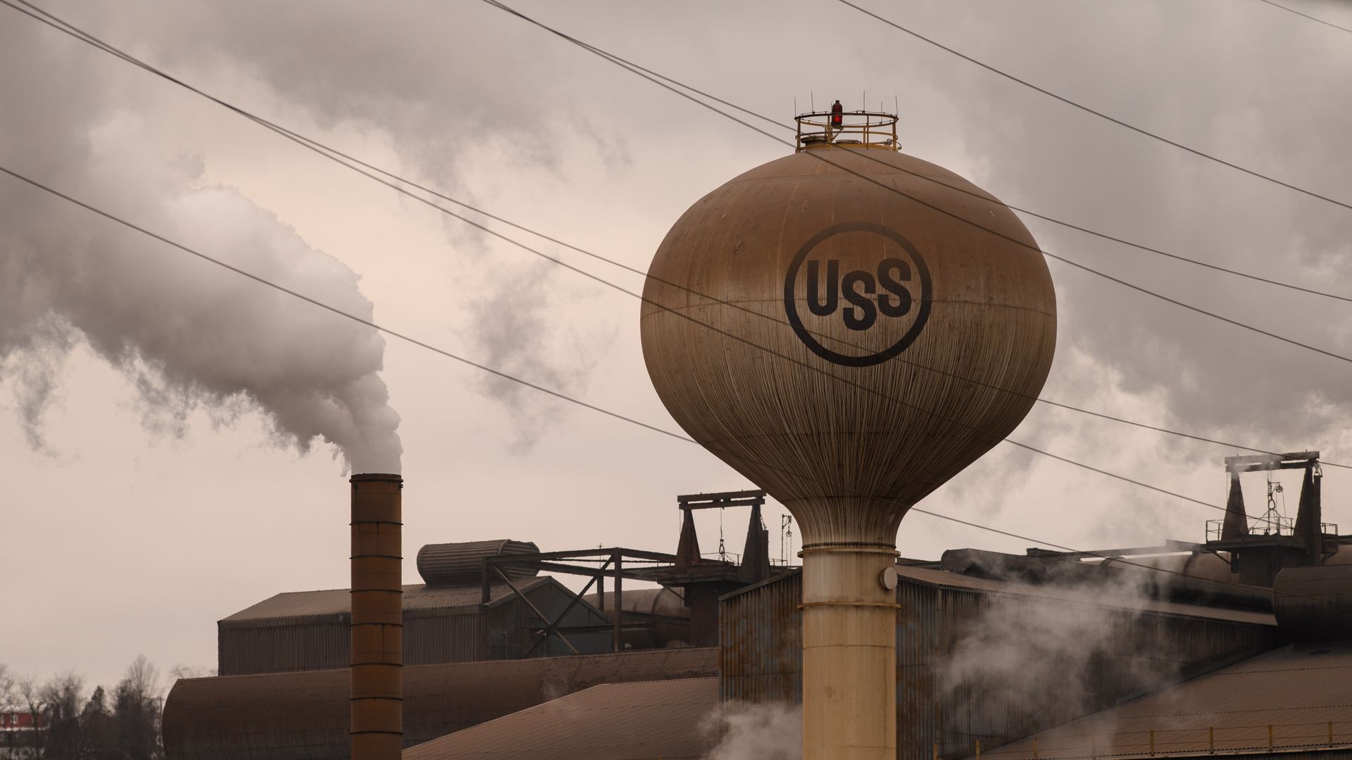 A steel plant with steam coming out of a chimney