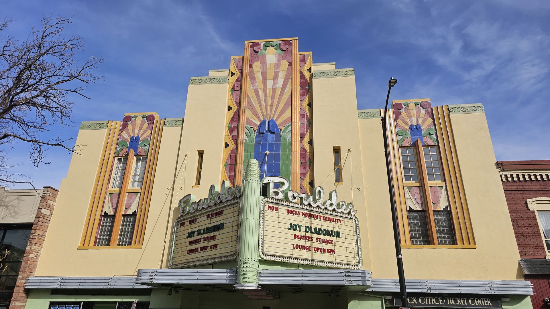 Art deco style Boulder Theater with colorful geometric designs and marquee advertising Joy Oladokun and Bartees Strange, under a clear blue sky.