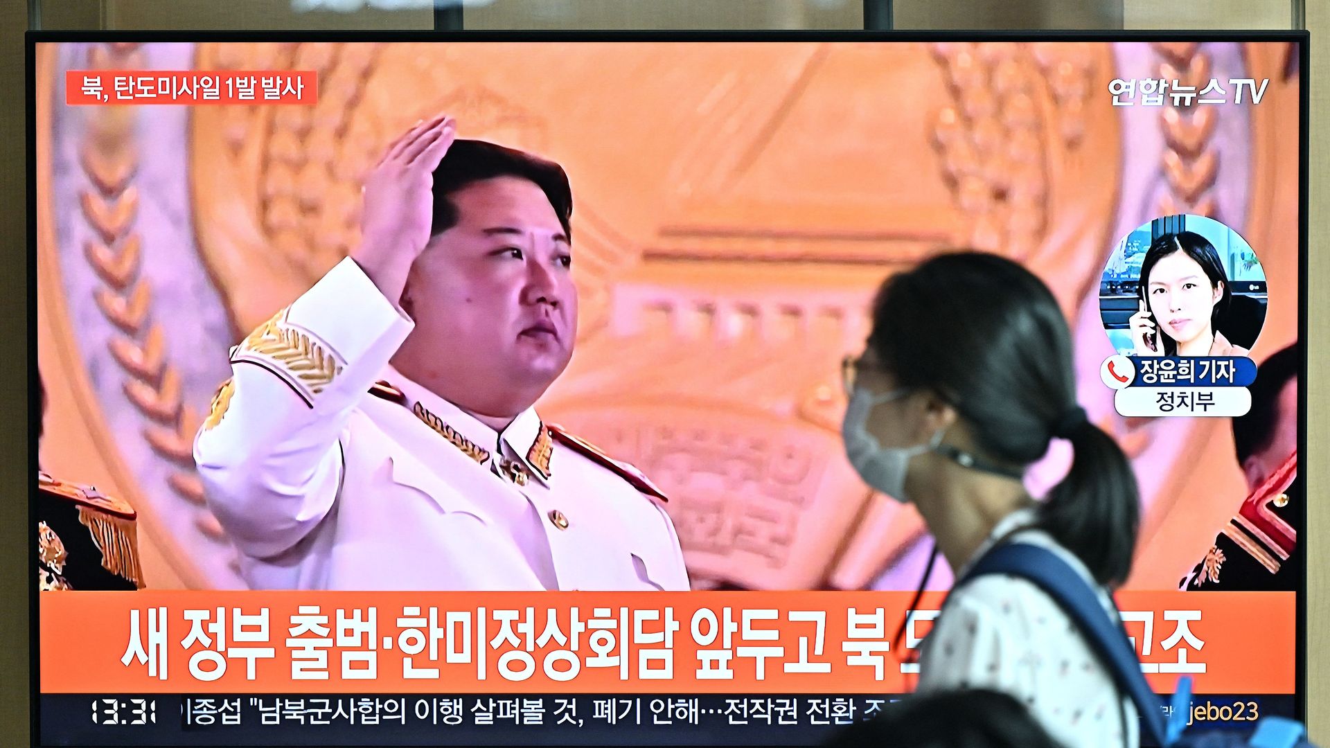A woman walks past a television screen showing a news broadcast with file footage of North Korean leader Kim Jong Un, at a railway station in Seoul on May 4.