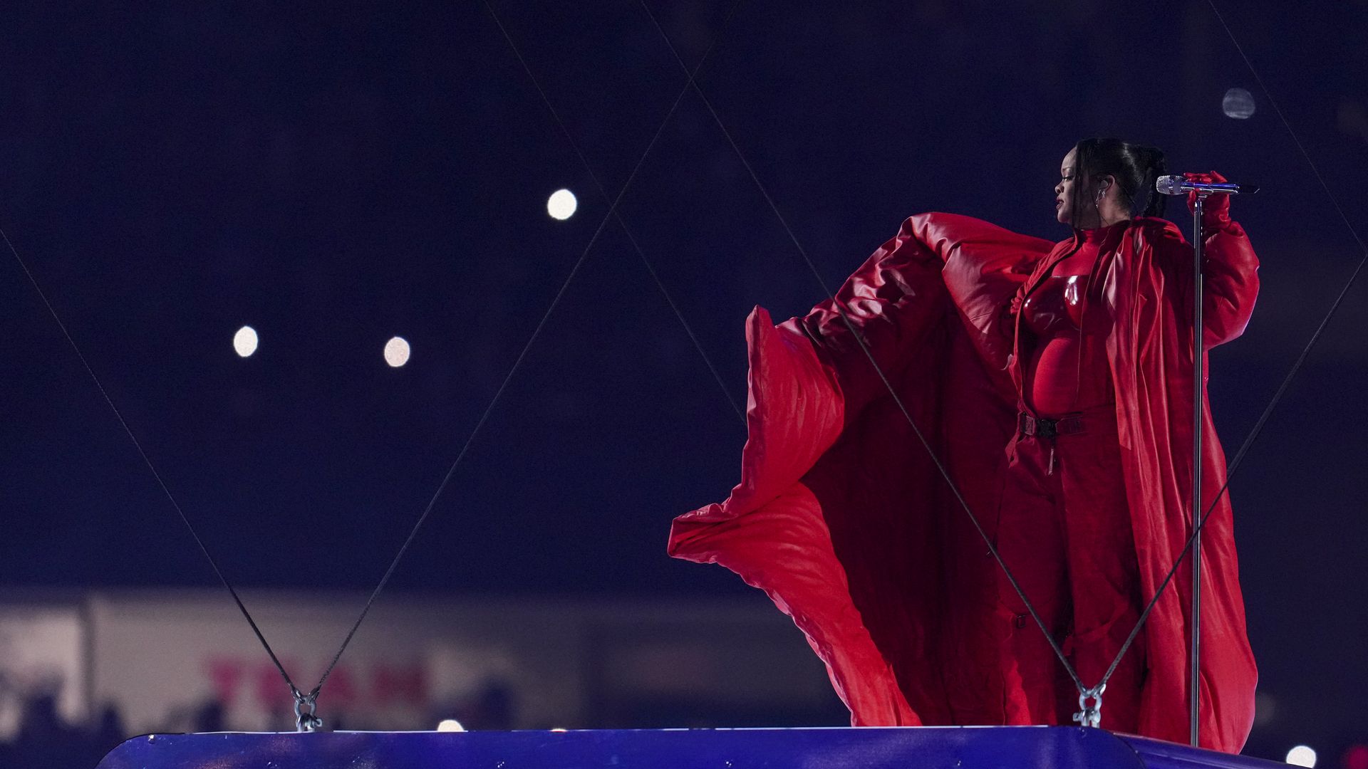 Rihanna, wearing all red, waves her coat during the Super Bowl halftime.