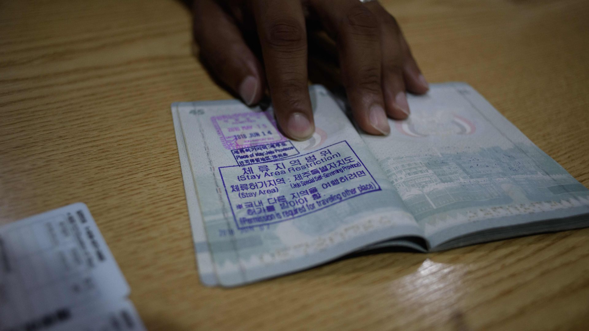 A hand holding open a foreign passport with a stamp in Korean